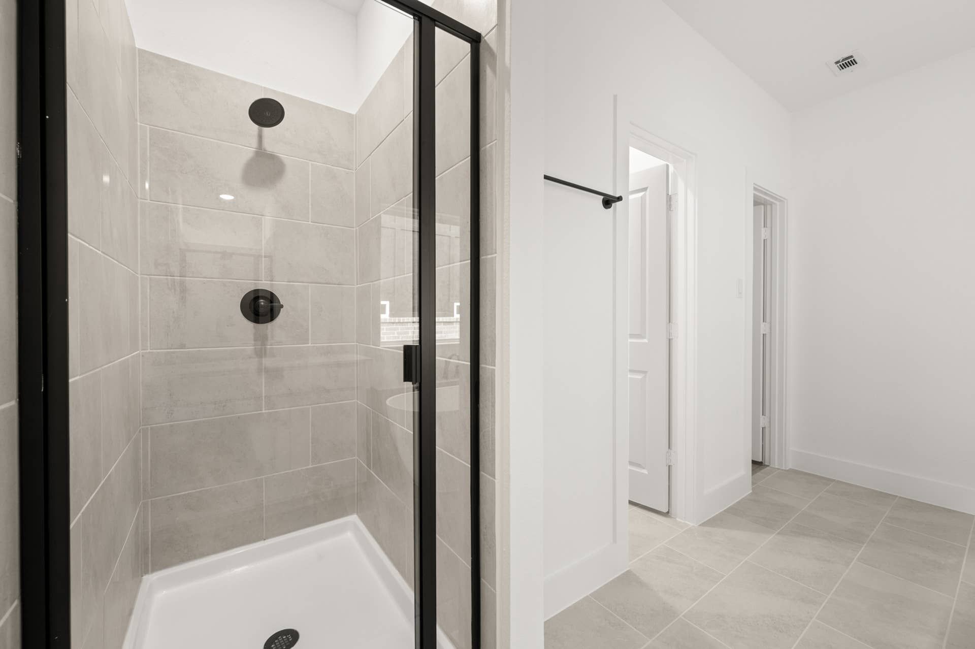 Modern bathroom with glass shower enclosure and large beige tiles.