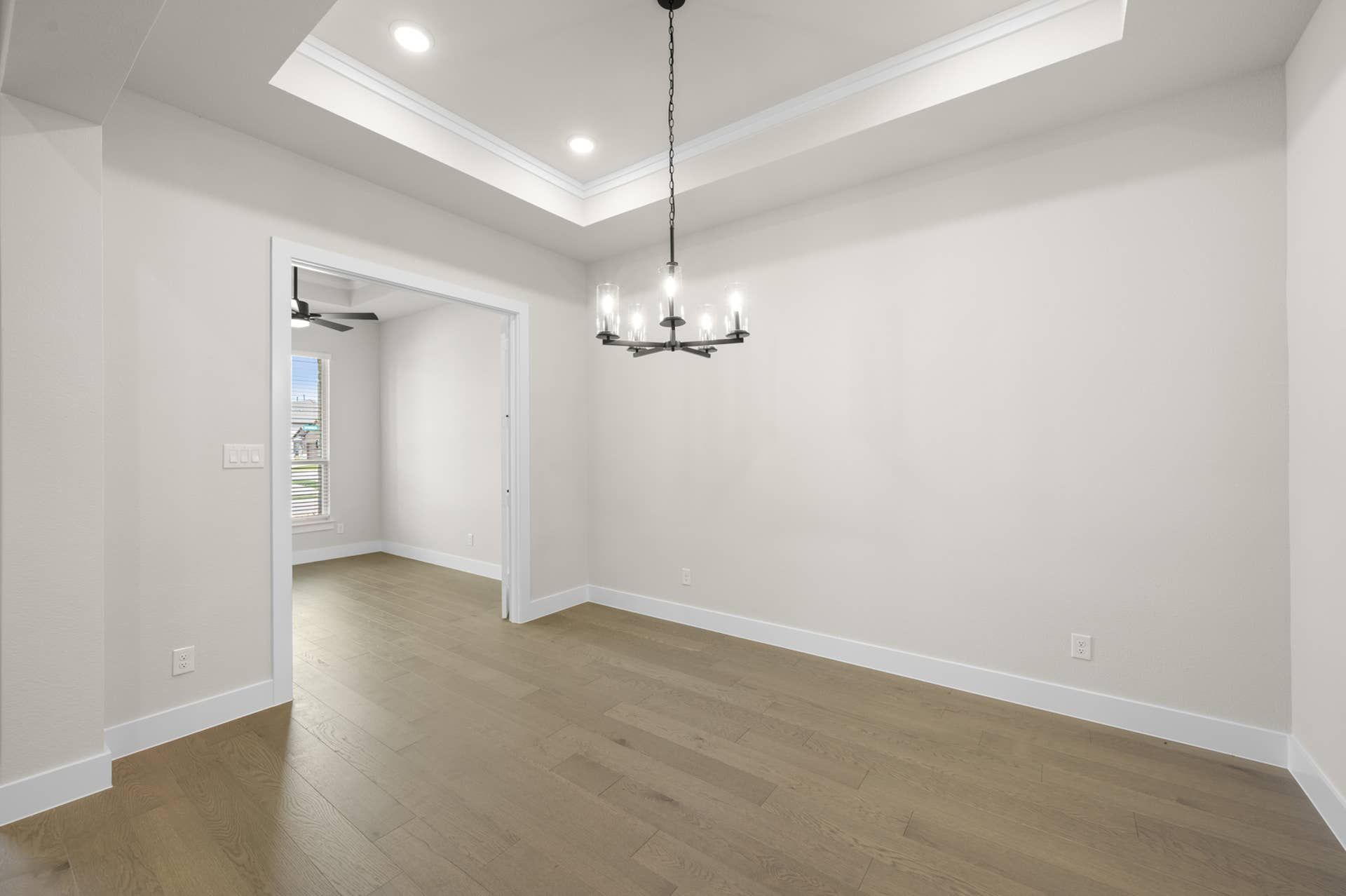 Spacious dining room with chandelier and tray ceiling.