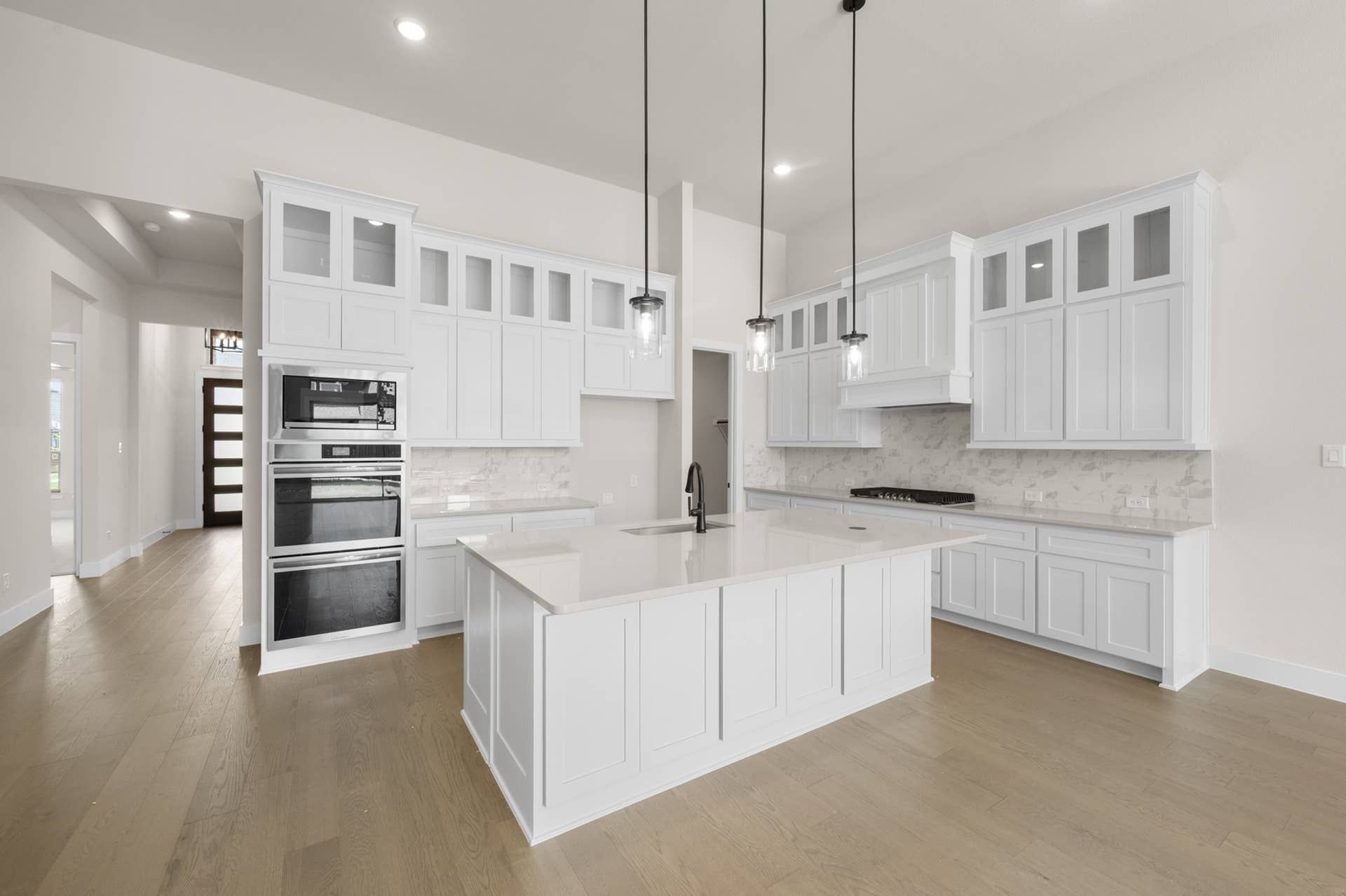 Spacious modern kitchen with white cabinetry, island, and pendant lighting.