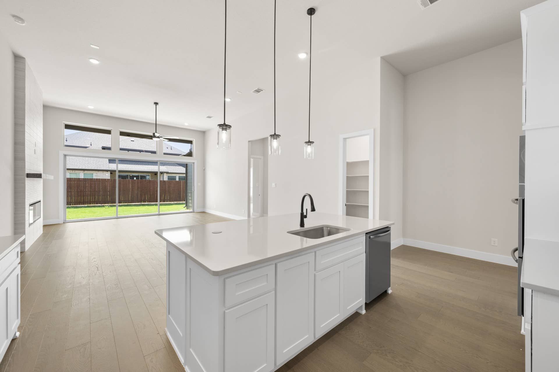 Modern kitchen with island, pendant lighting, and large sliding glass doors.