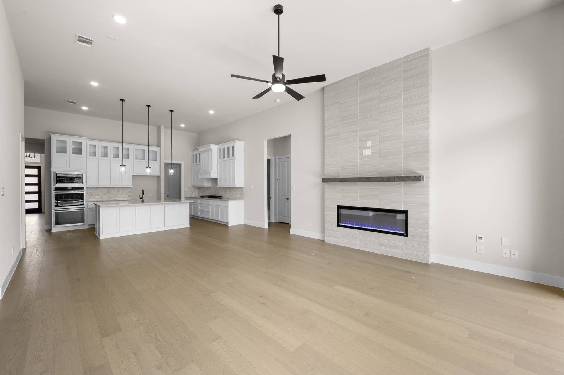 Spacious open-concept living room with modern kitchen and sleek fireplace.