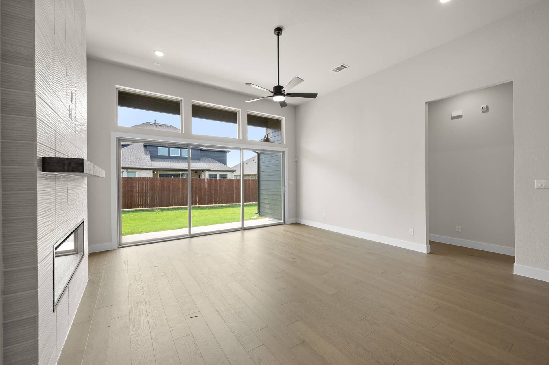 Spacious living room with large windows, ceiling fan, and modern fireplace.