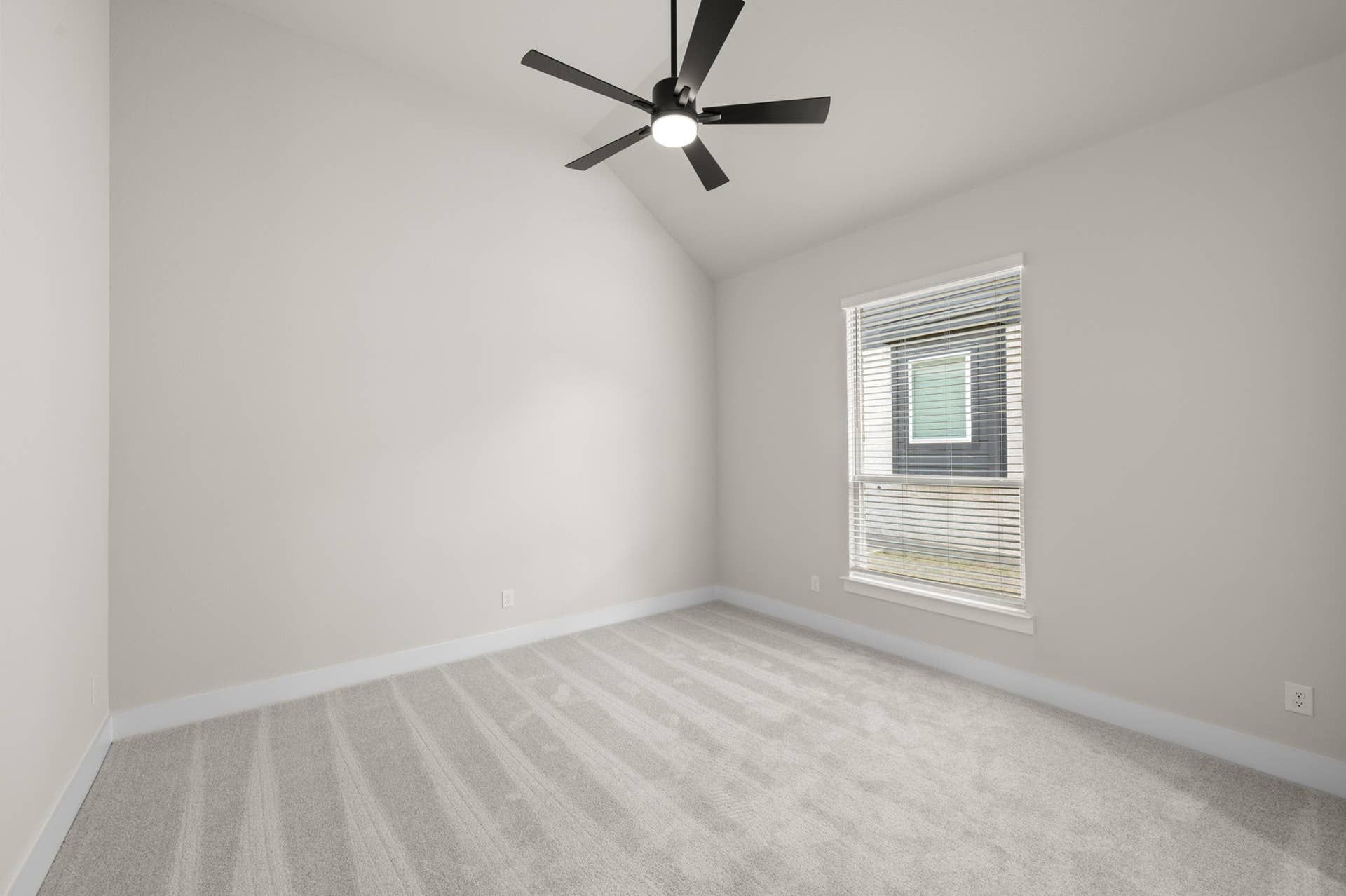 Spacious bedroom with ceiling fan and window with blinds, featuring neutral tones.