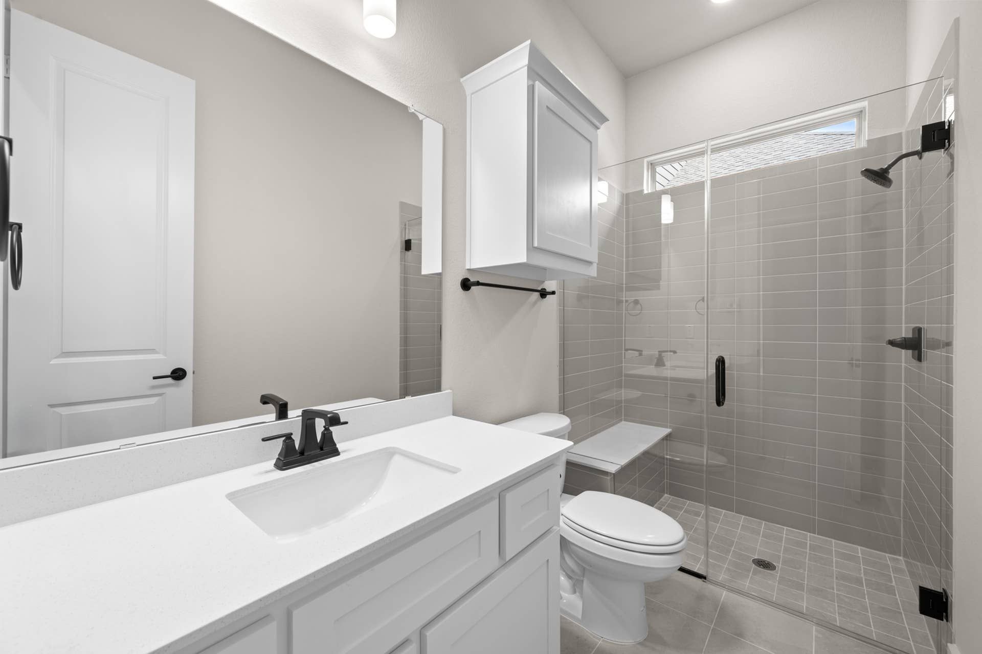 Modern bathroom with glass shower, white vanity, and sleek fixtures.