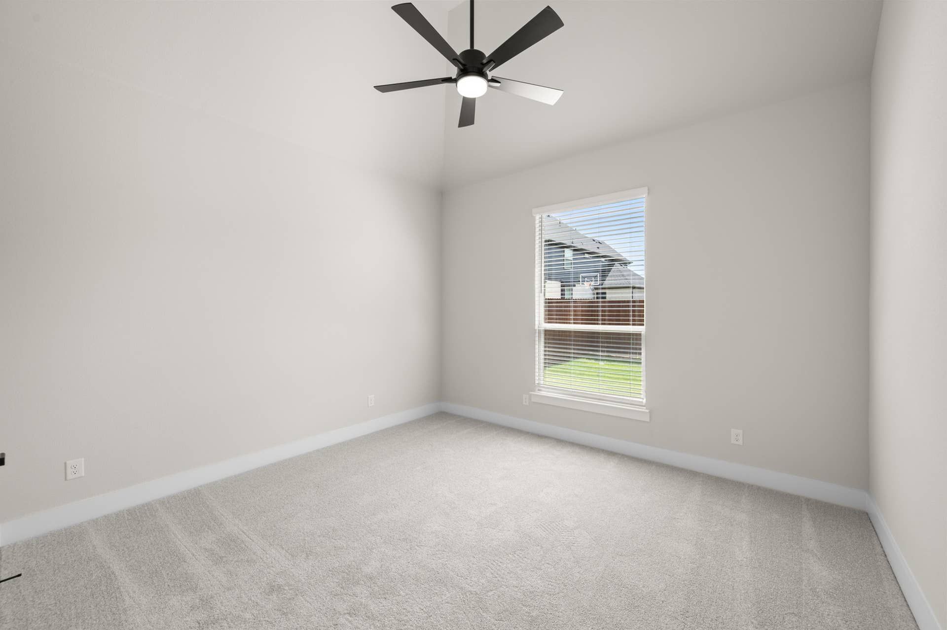 Spacious bedroom with neutral walls, carpet flooring, and ceiling fan.