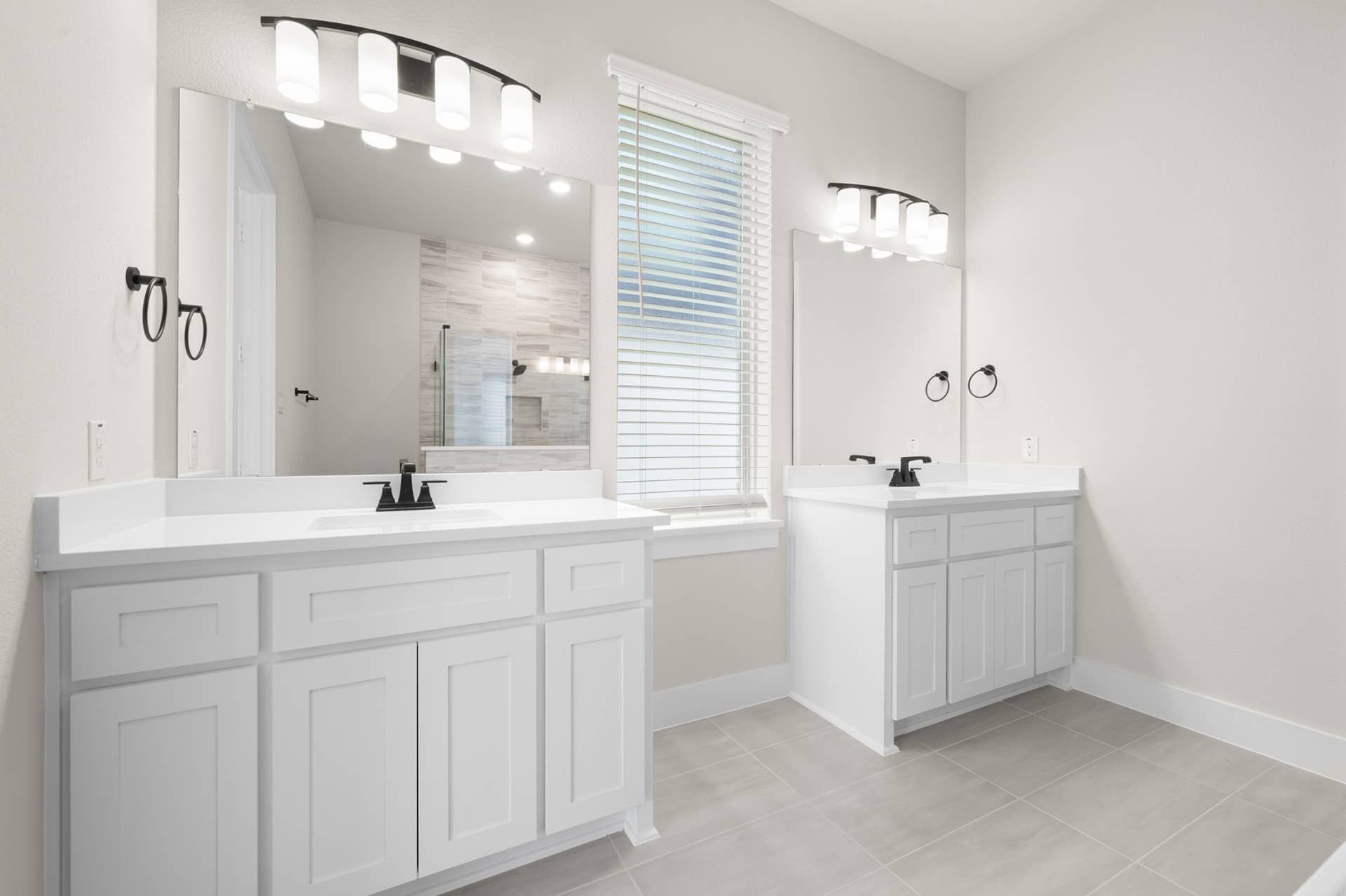 Spacious primary suite bathroom with dual vanities and modern lighting.