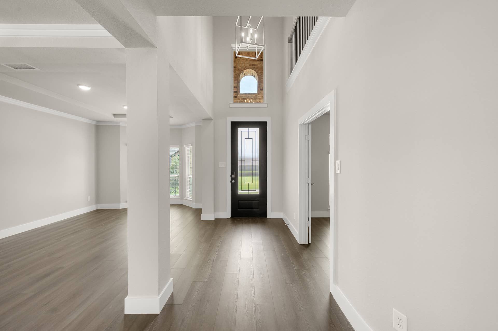 Spacious modern entryway with high ceiling and elegant black front door.