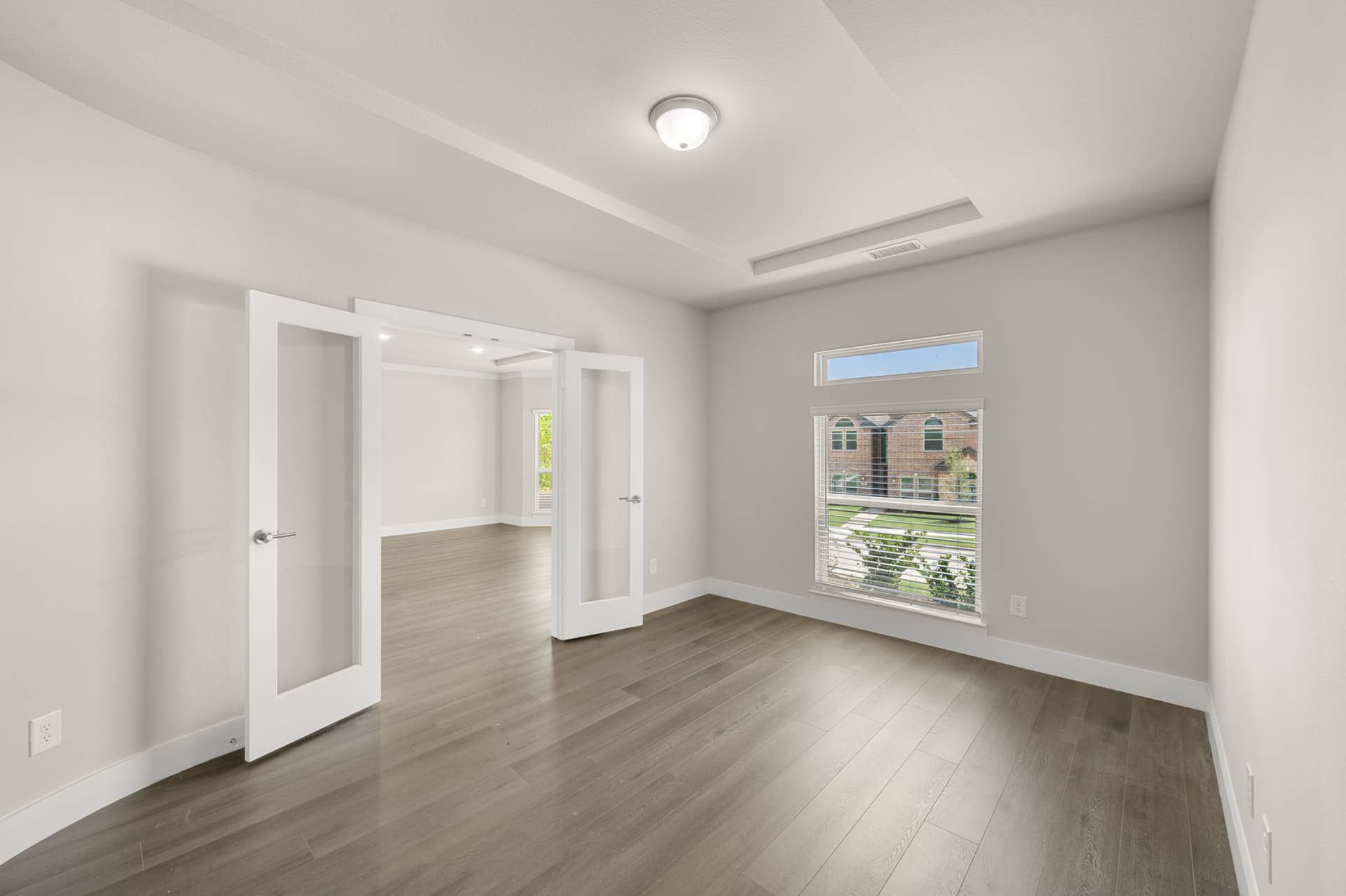 Modern study room with glass French doors and large window overlooking the exterior.