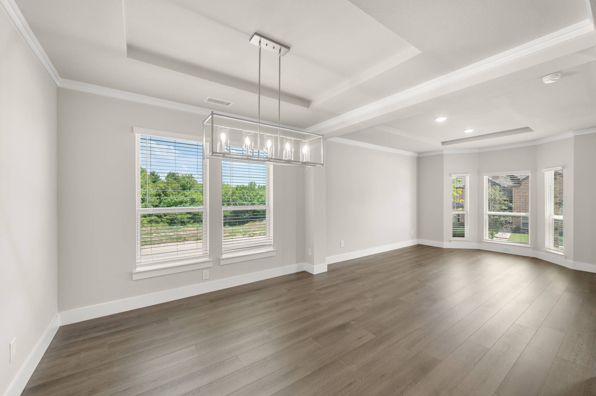 Spacious interior with elegant tray ceiling and modern chandelier.
