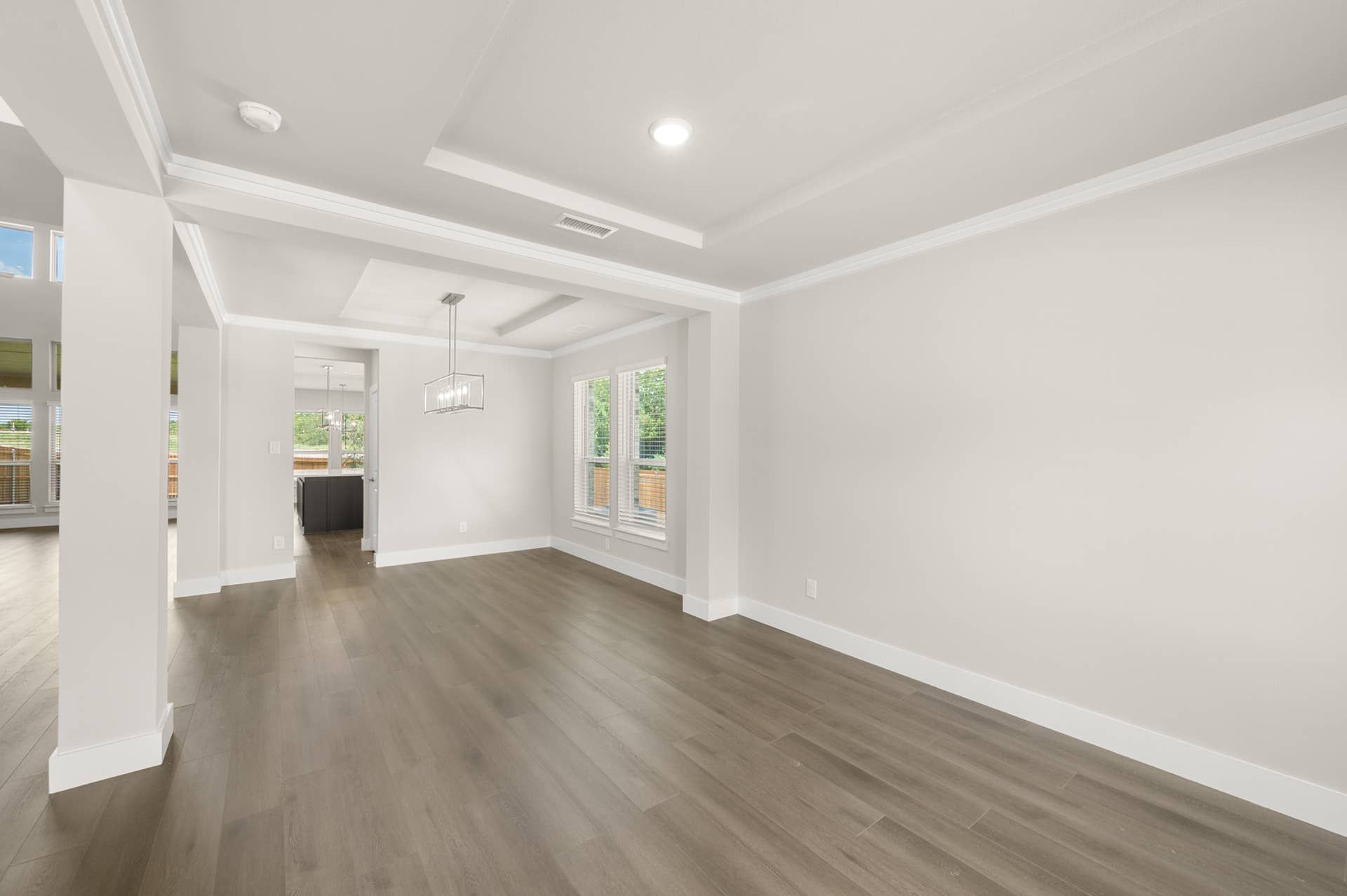 Spacious modern interior with wood flooring and large windows in flex space.