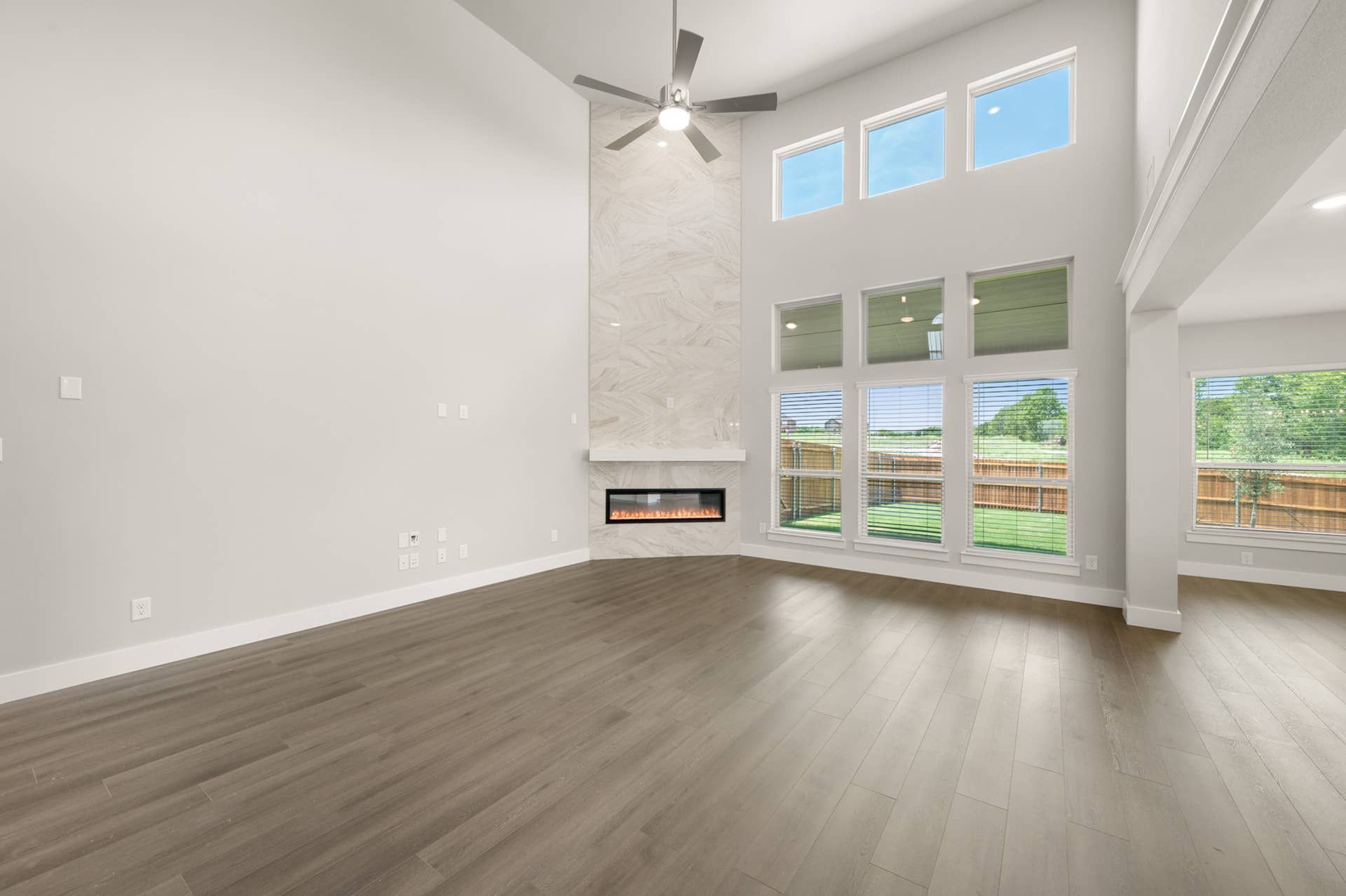 Spacious living room with high ceilings, large windows, and modern fireplace.