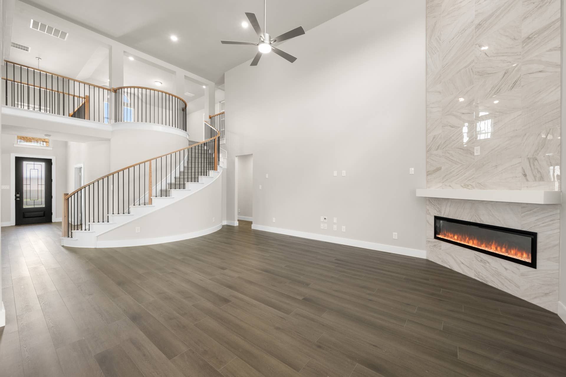 Spacious living room with modern fireplace and elegant curved staircase.