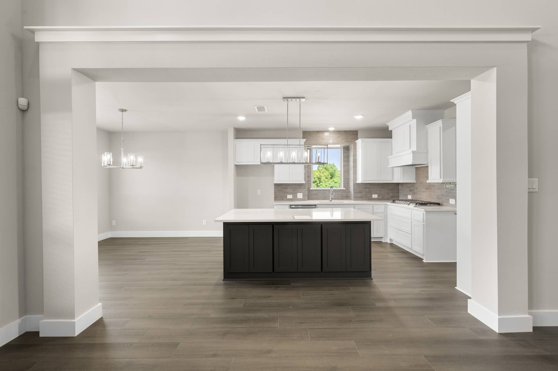 Modern kitchen with dark island, white cabinets, and hardwood floors.