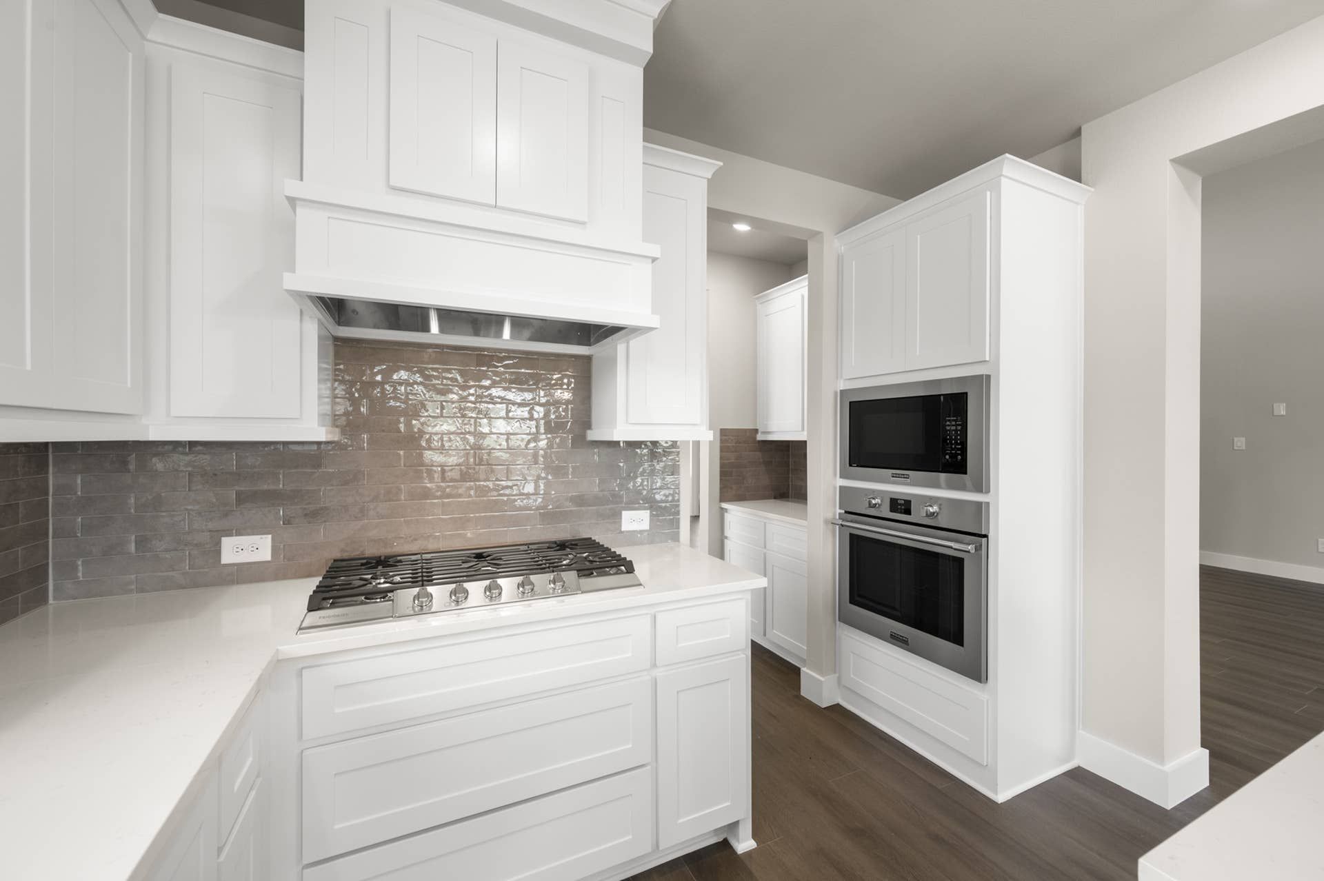 Modern kitchen with white cabinetry, gas cooktop, and built-in oven and microwave.