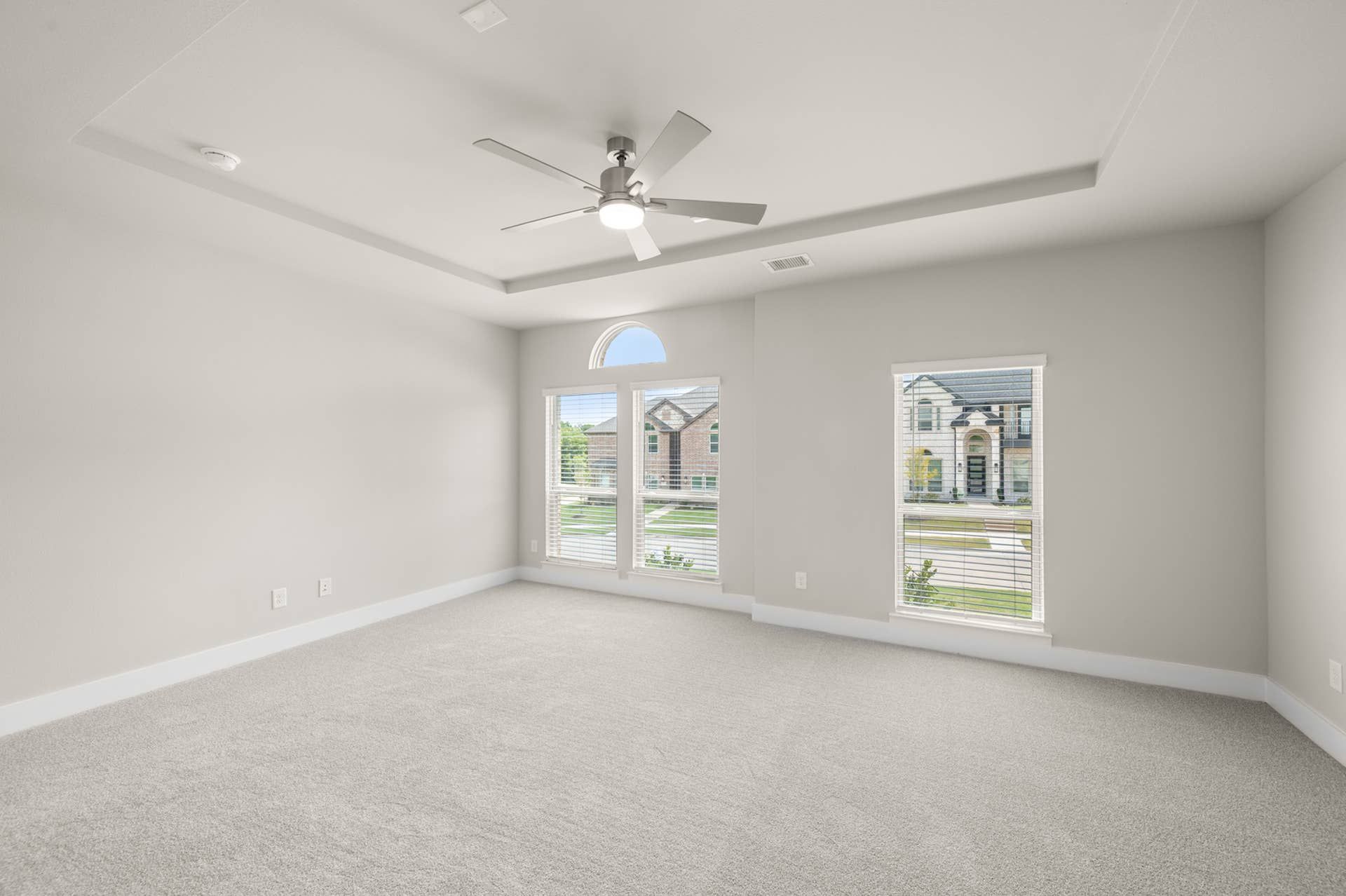 Spacious primary suite with tray ceiling and large windows.