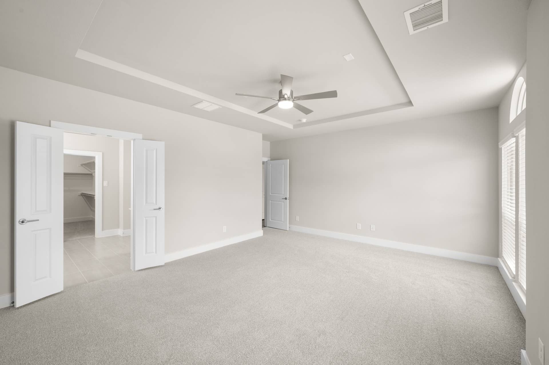 Spacious primary suite with tray ceiling and walk-in closet entrance.