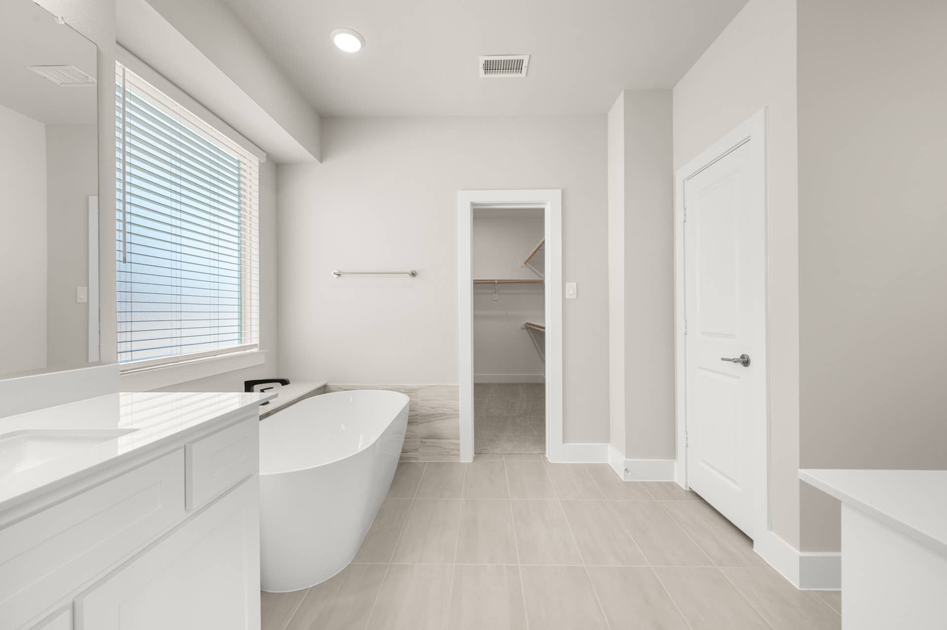 Modern bathroom with freestanding tub and walk-in closet entry.