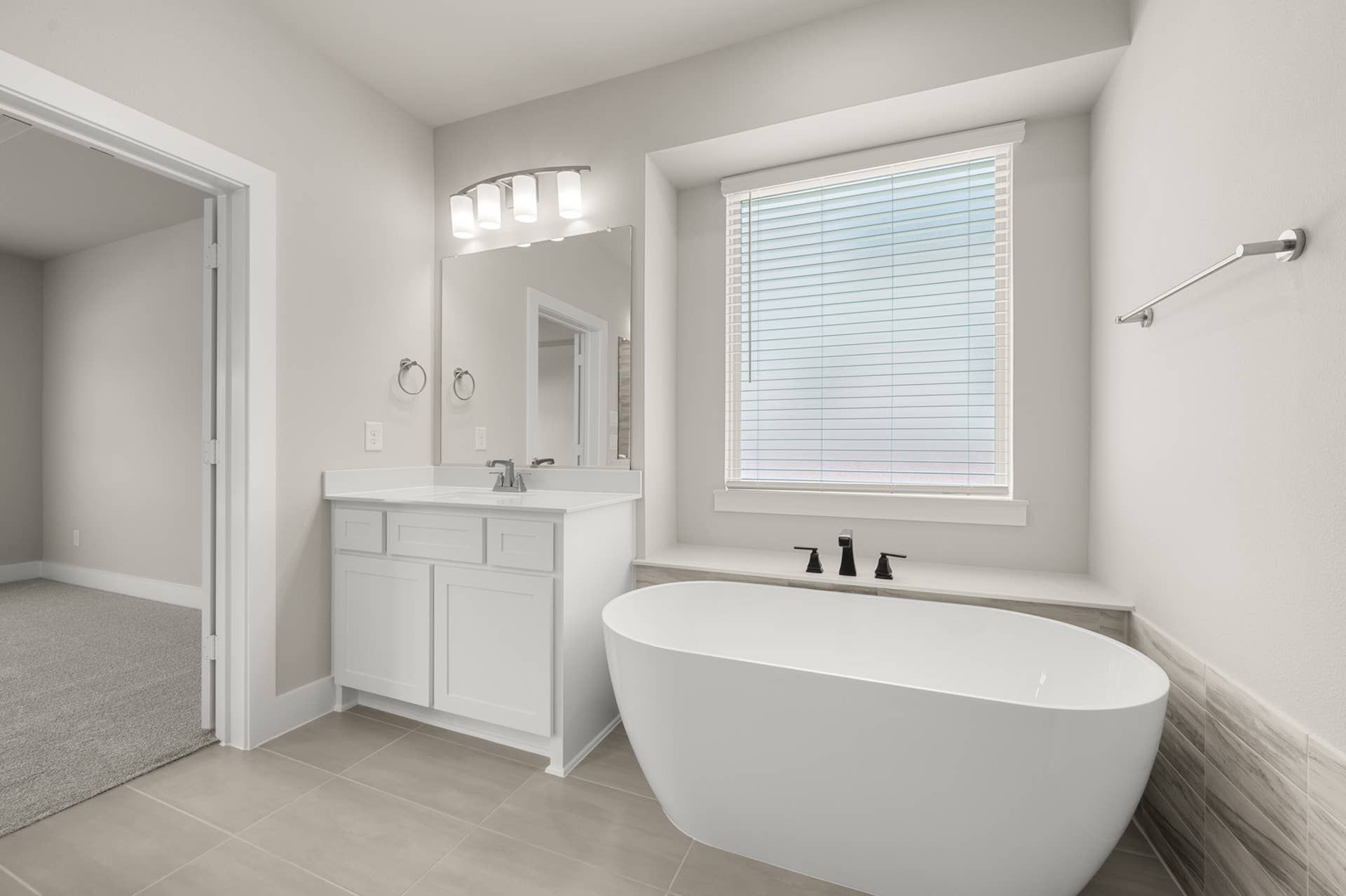 Spacious modern bathroom with freestanding tub and white vanity.