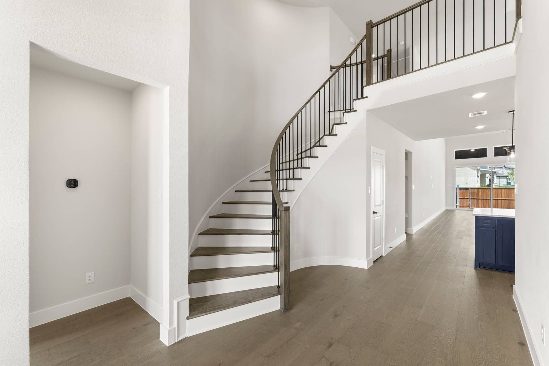 Elegant curved staircase with wooden steps and modern railing in spacious entryway.