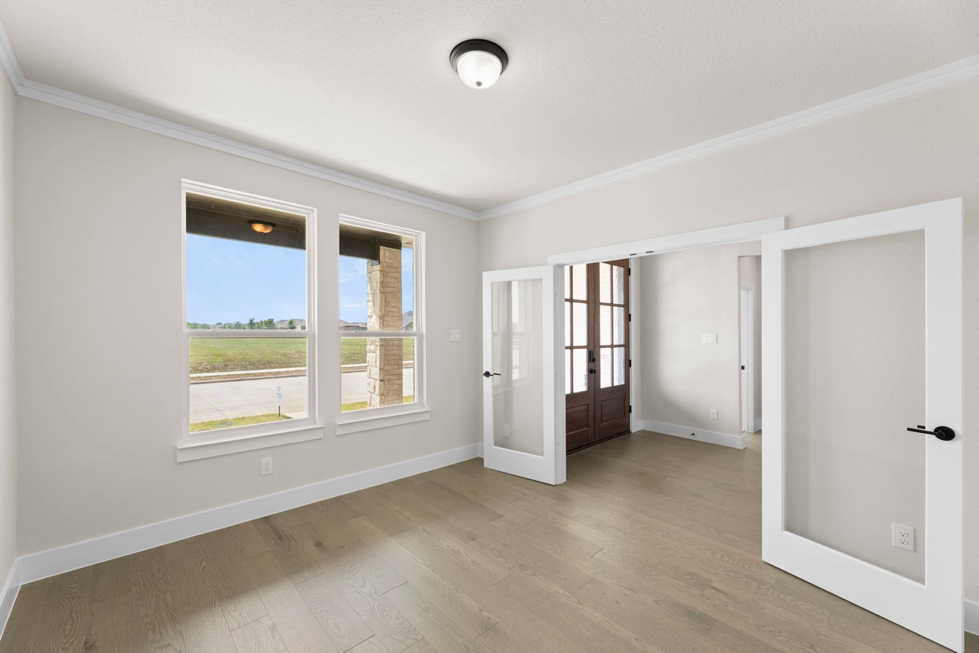 Bright study with glass doors and large windows overlooking a serene landscape.