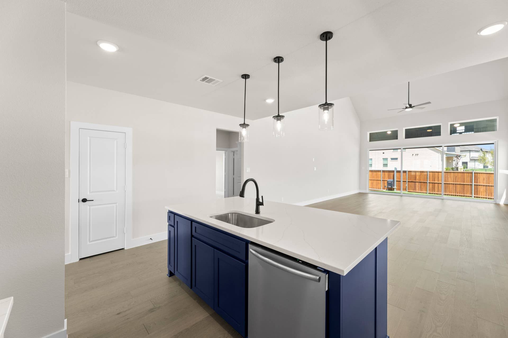 Modern kitchen with blue island, pendant lights, and open living space.