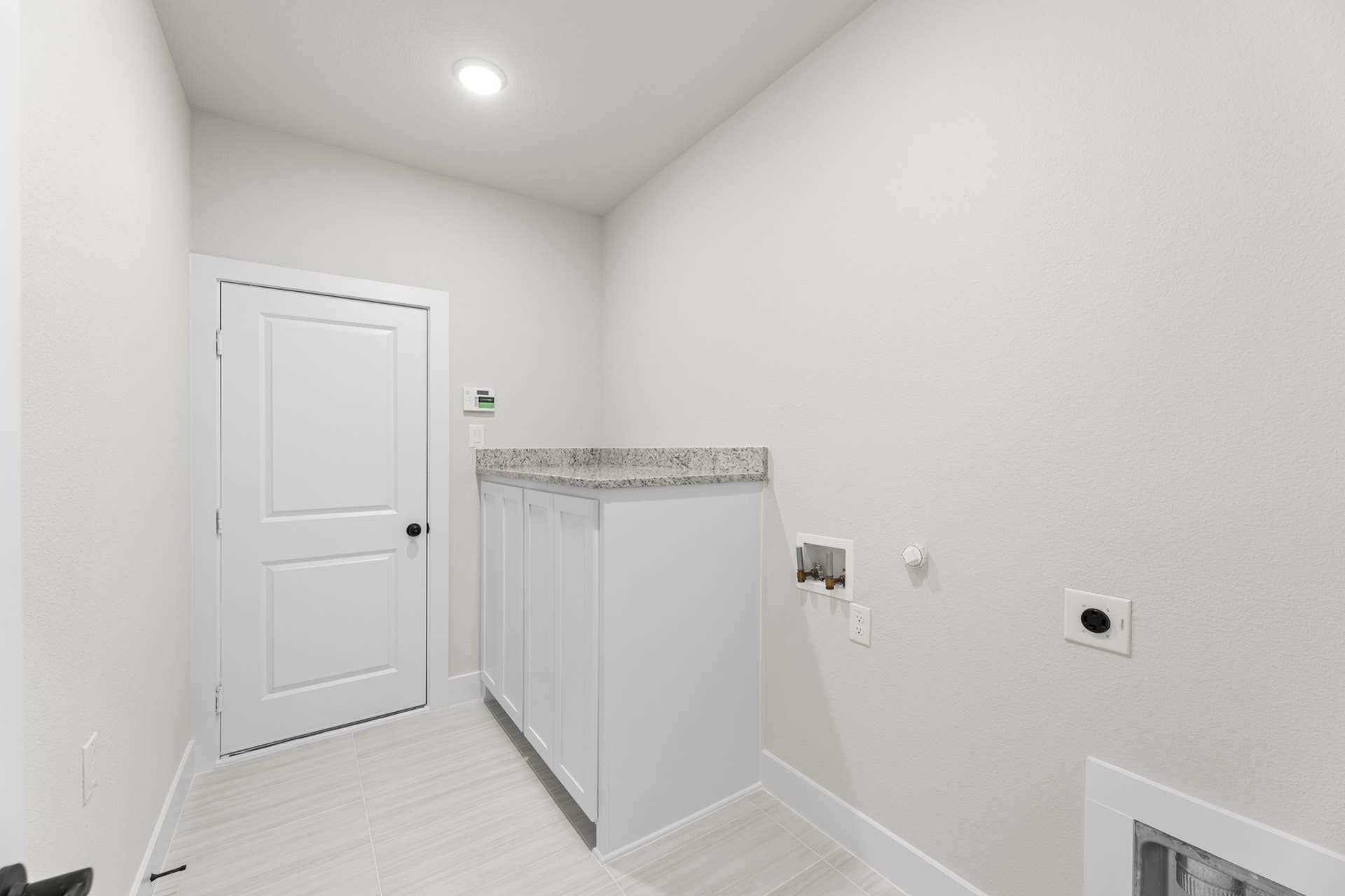 Modern utility room with light cabinetry and washer-dryer hookups.