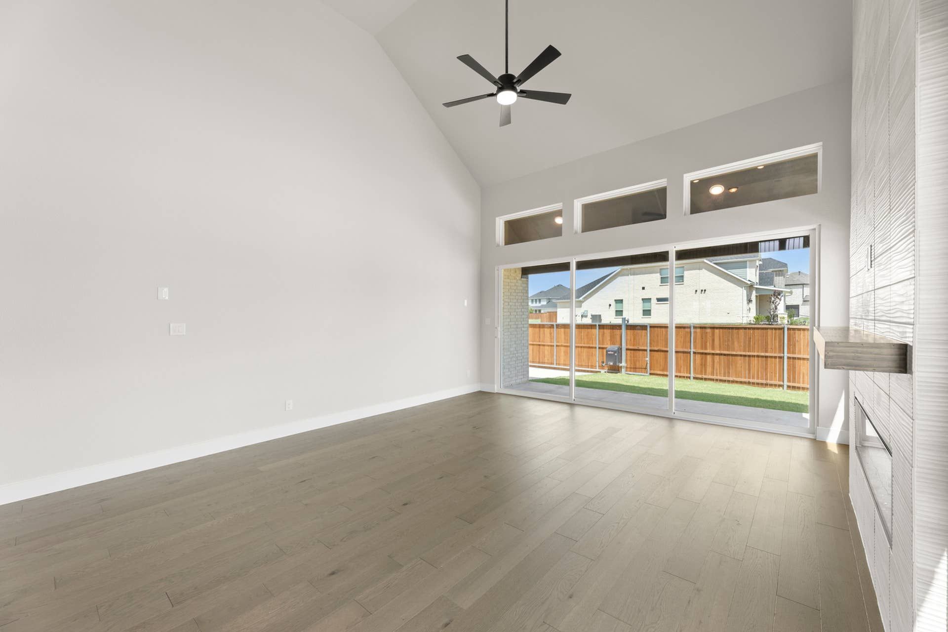 Spacious living room with vaulted ceiling and large windows overlooking backyard.