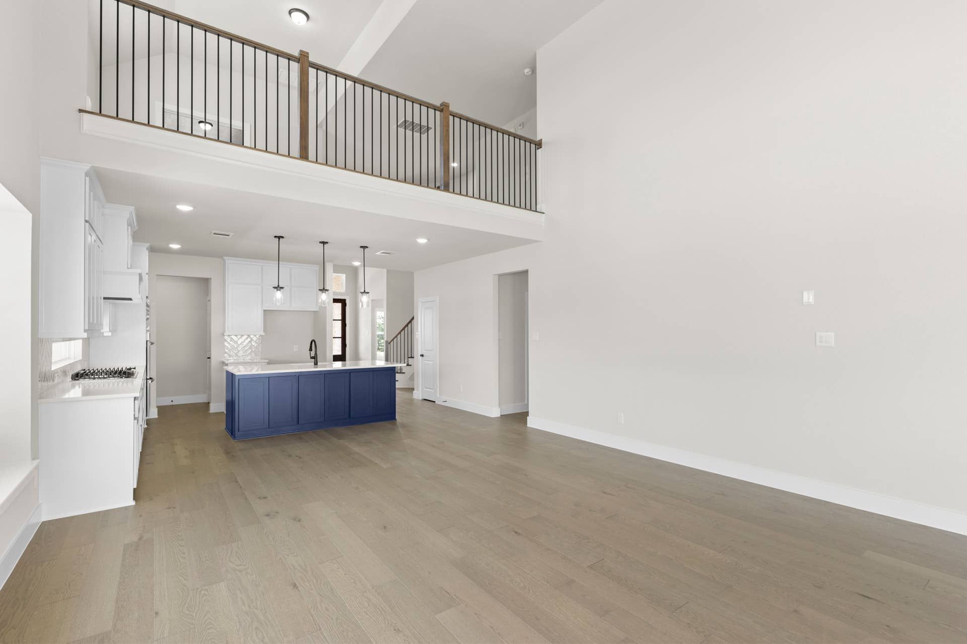 Spacious open-plan interior with high ceilings, loft, and modern kitchen island.