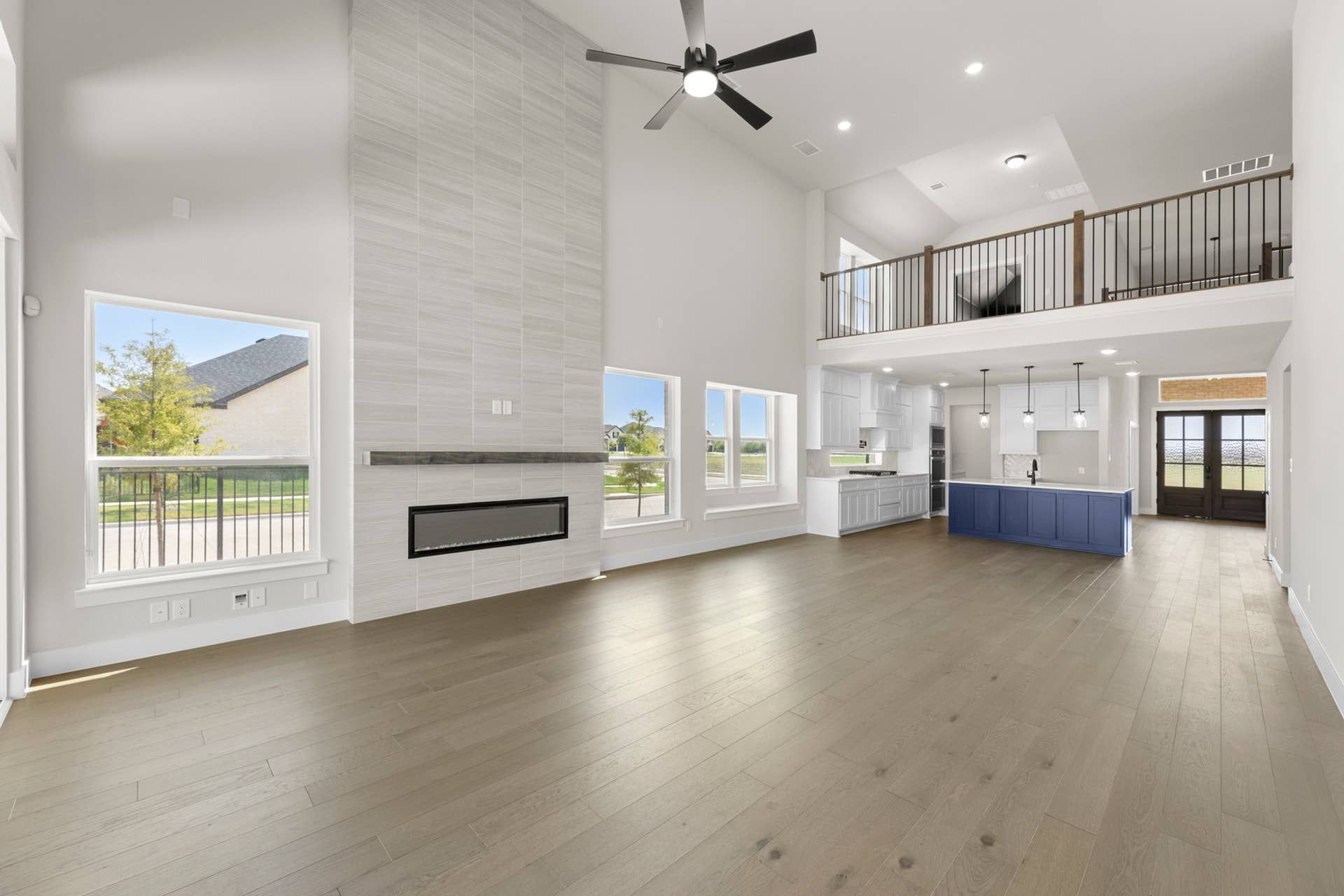 Spacious modern living area with high ceilings, fireplace, and open kitchen design.