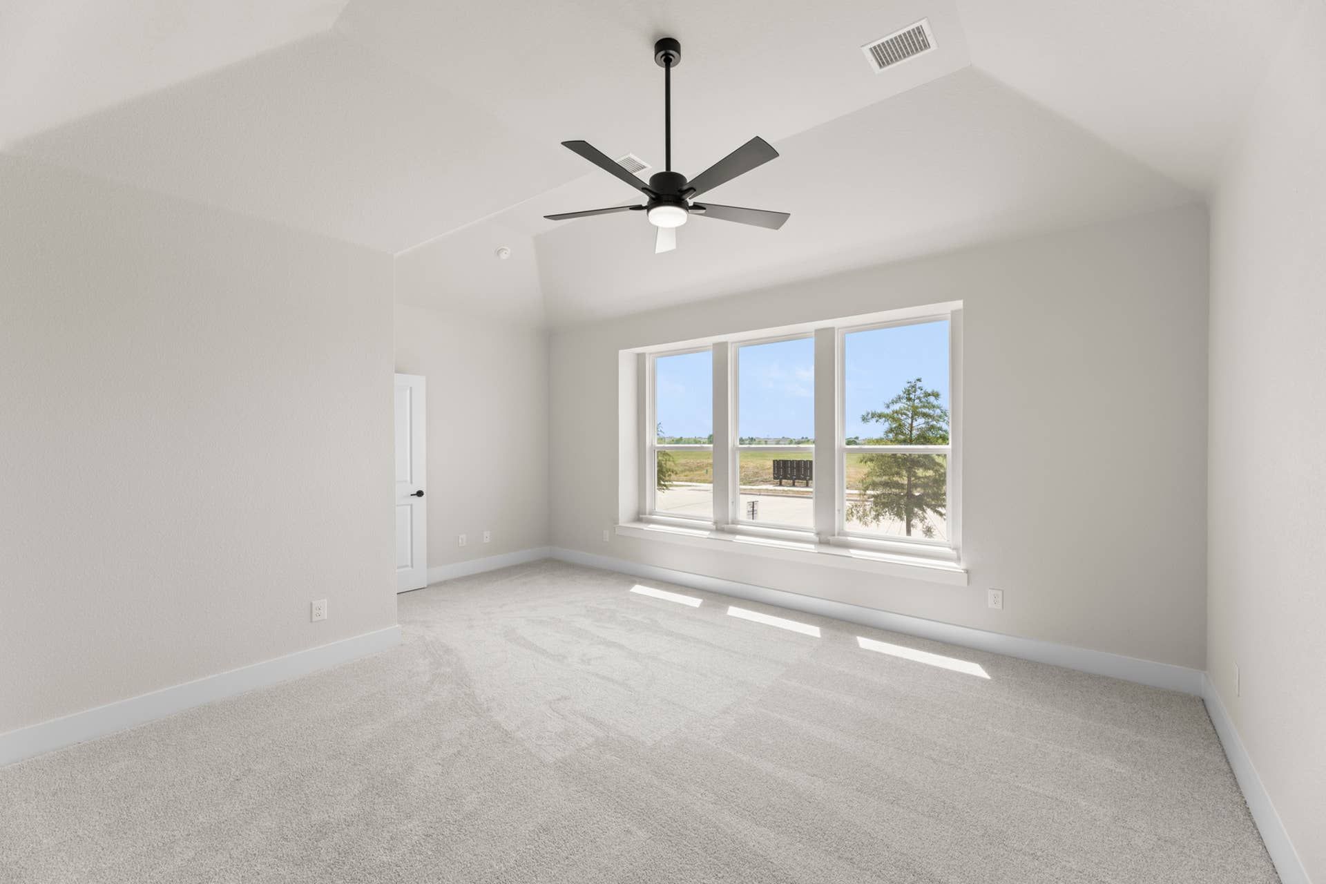 Spacious, light-filled room with large windows and modern ceiling fan.