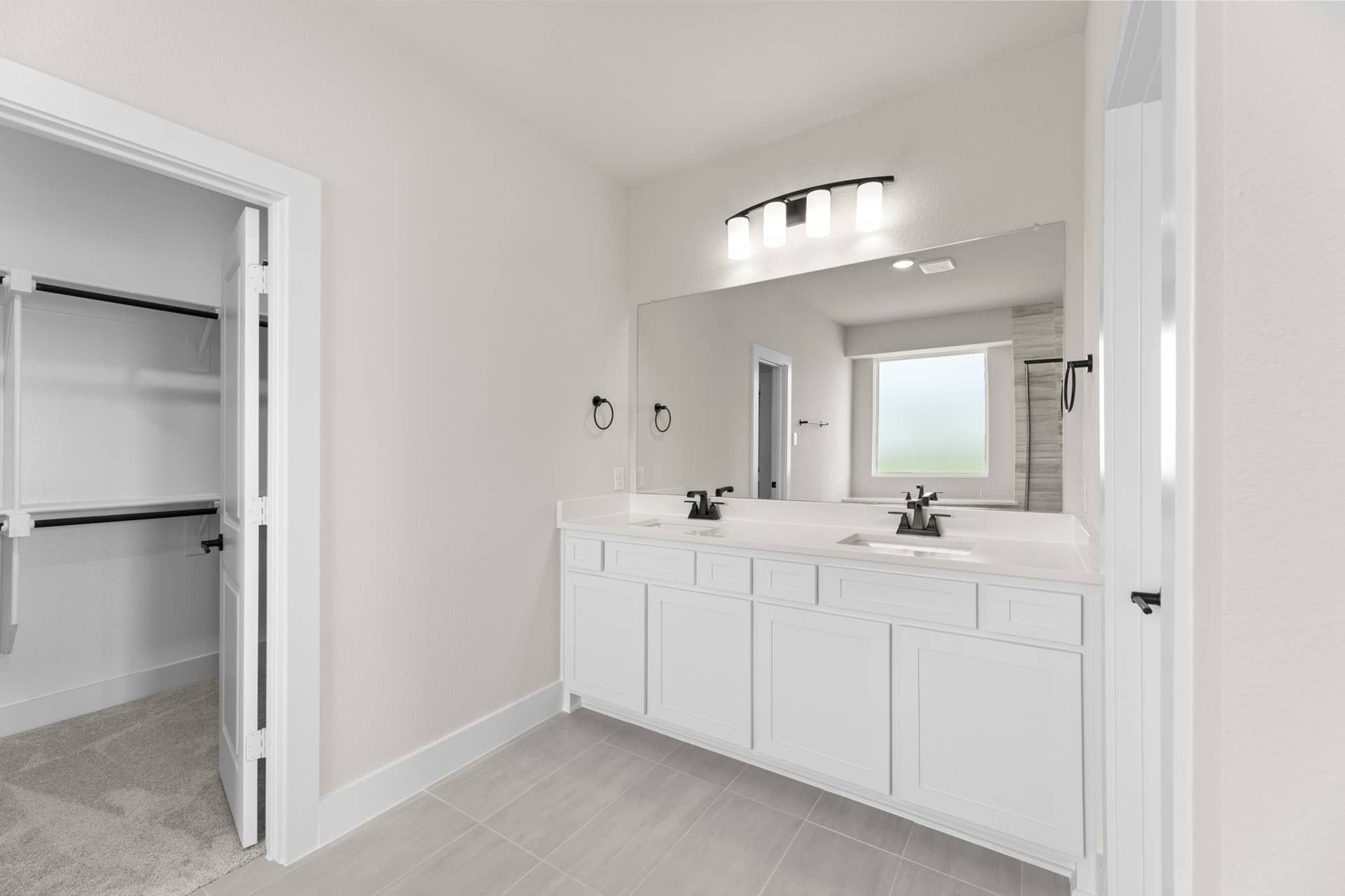 Modern bathroom with double sink vanity and spacious walk-in closet.
