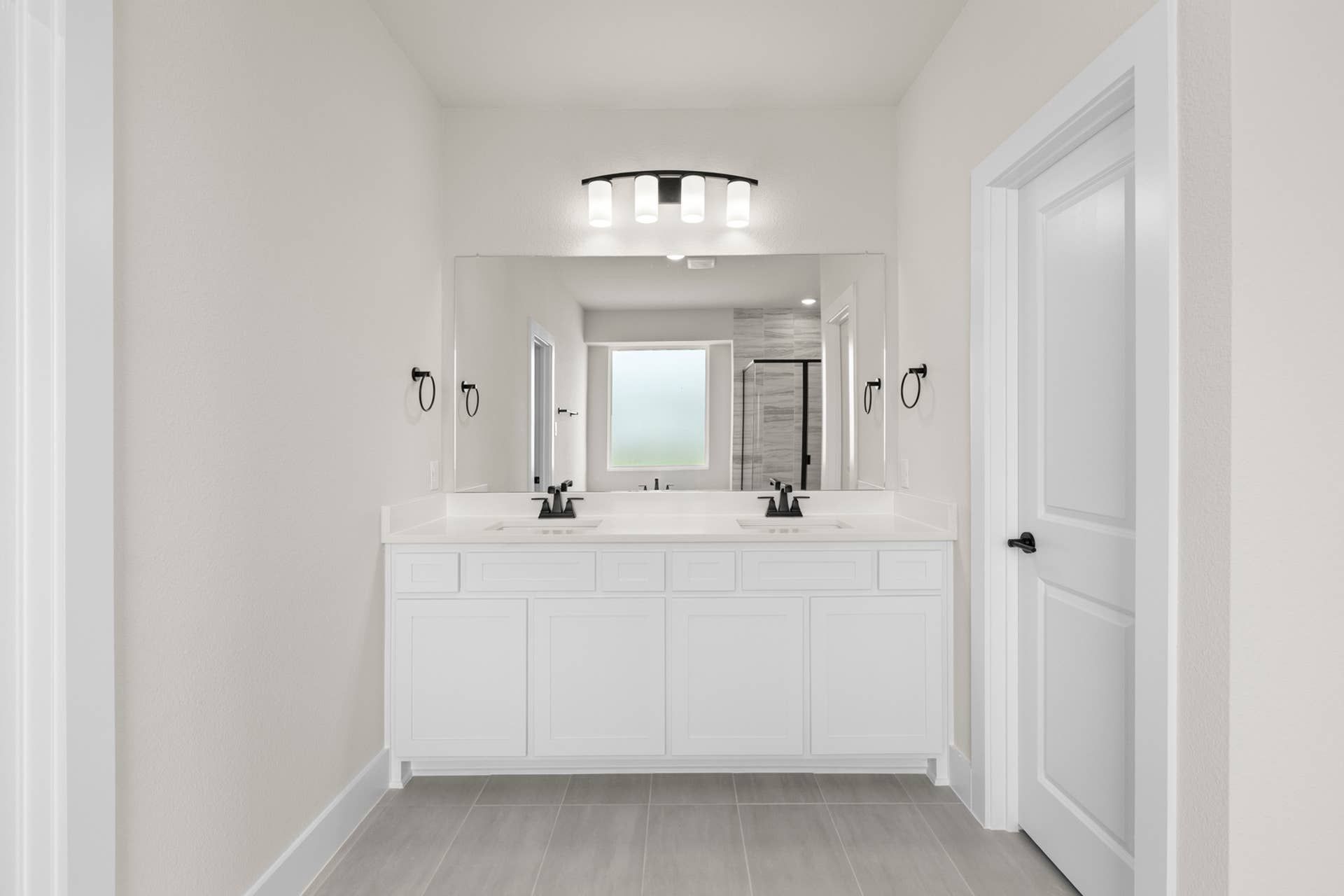 Modern bathroom with double vanity, large mirror, and sleek light fixtures.