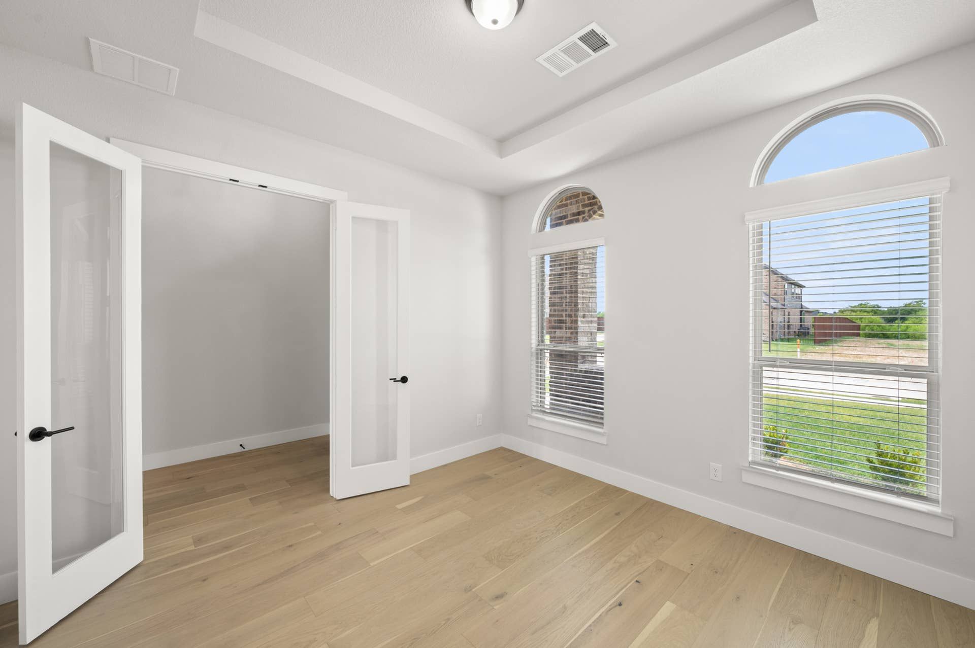 Bright study room with French doors and large windows.