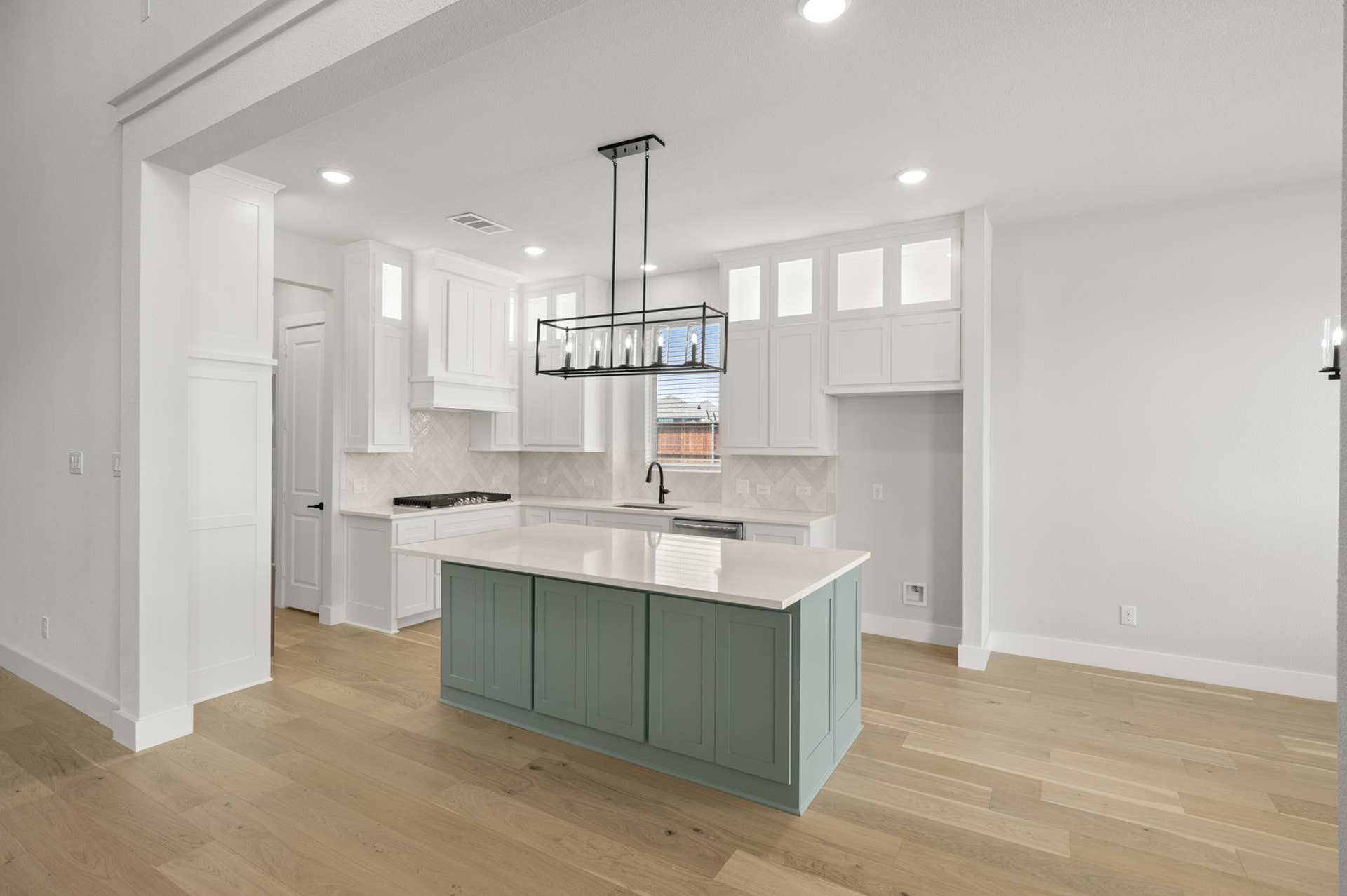 Modern kitchen with white cabinets, teal island, and pendant lighting.