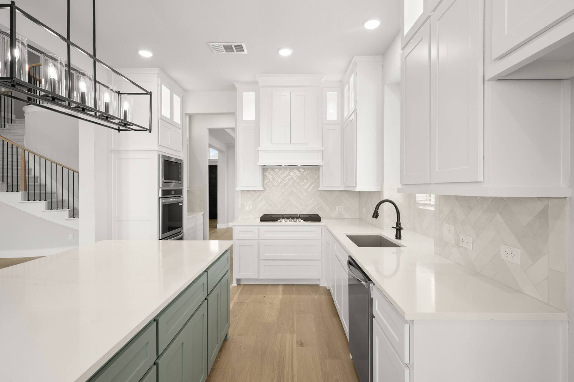Modern kitchen with white cabinetry, island, and herringbone backsplash.