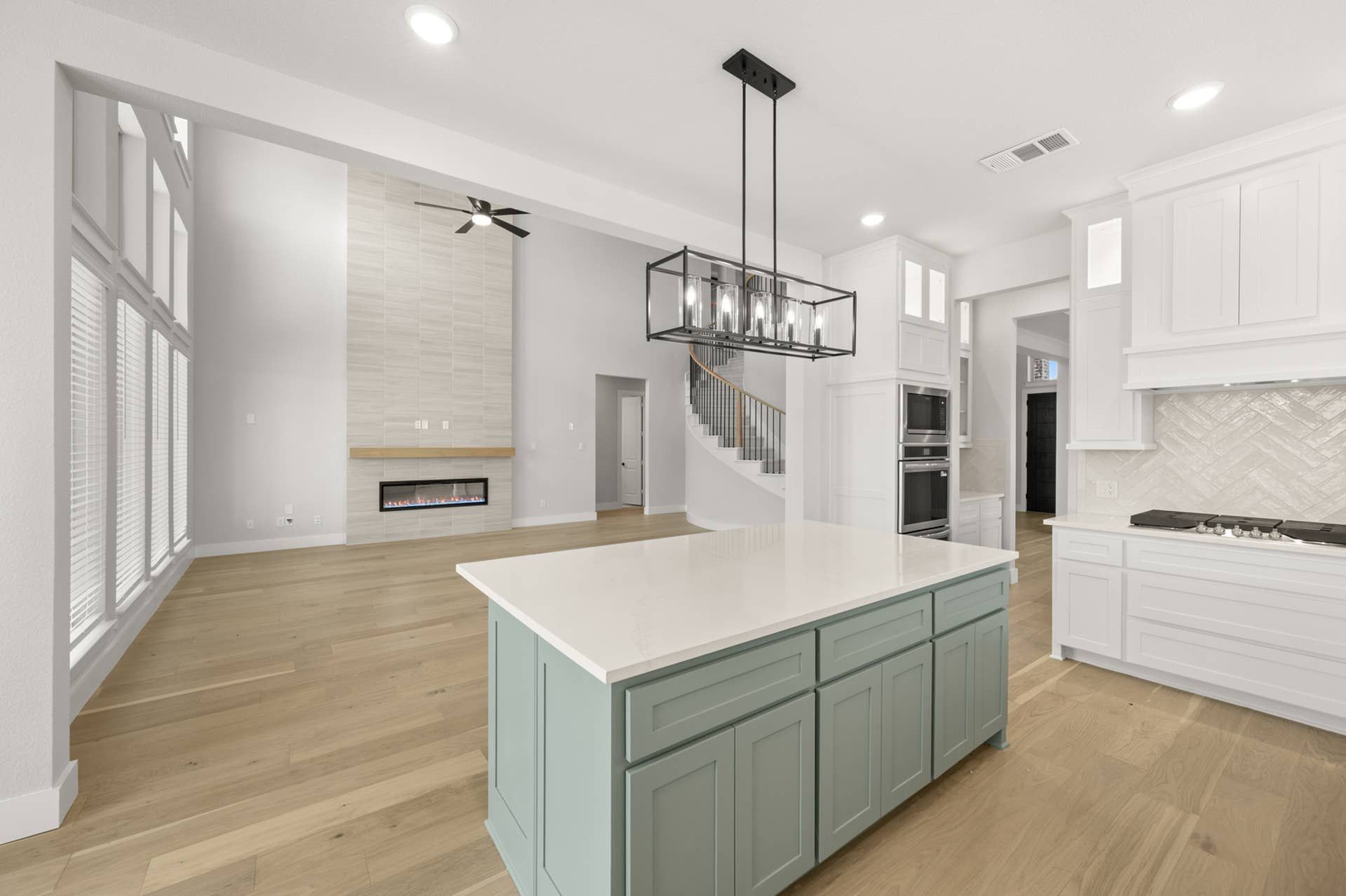 Modern kitchen with island, open floor plan, and elegant light fixture.