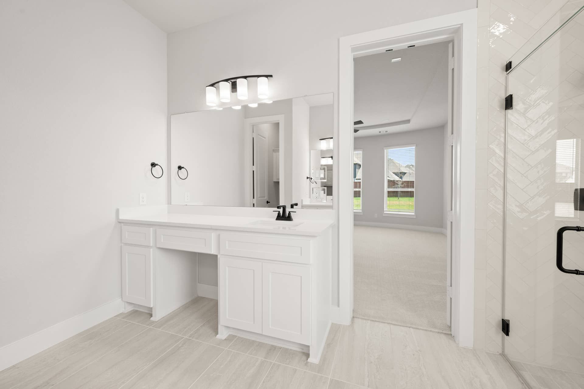 Spacious primary suite bathroom with modern vanity and large mirror.