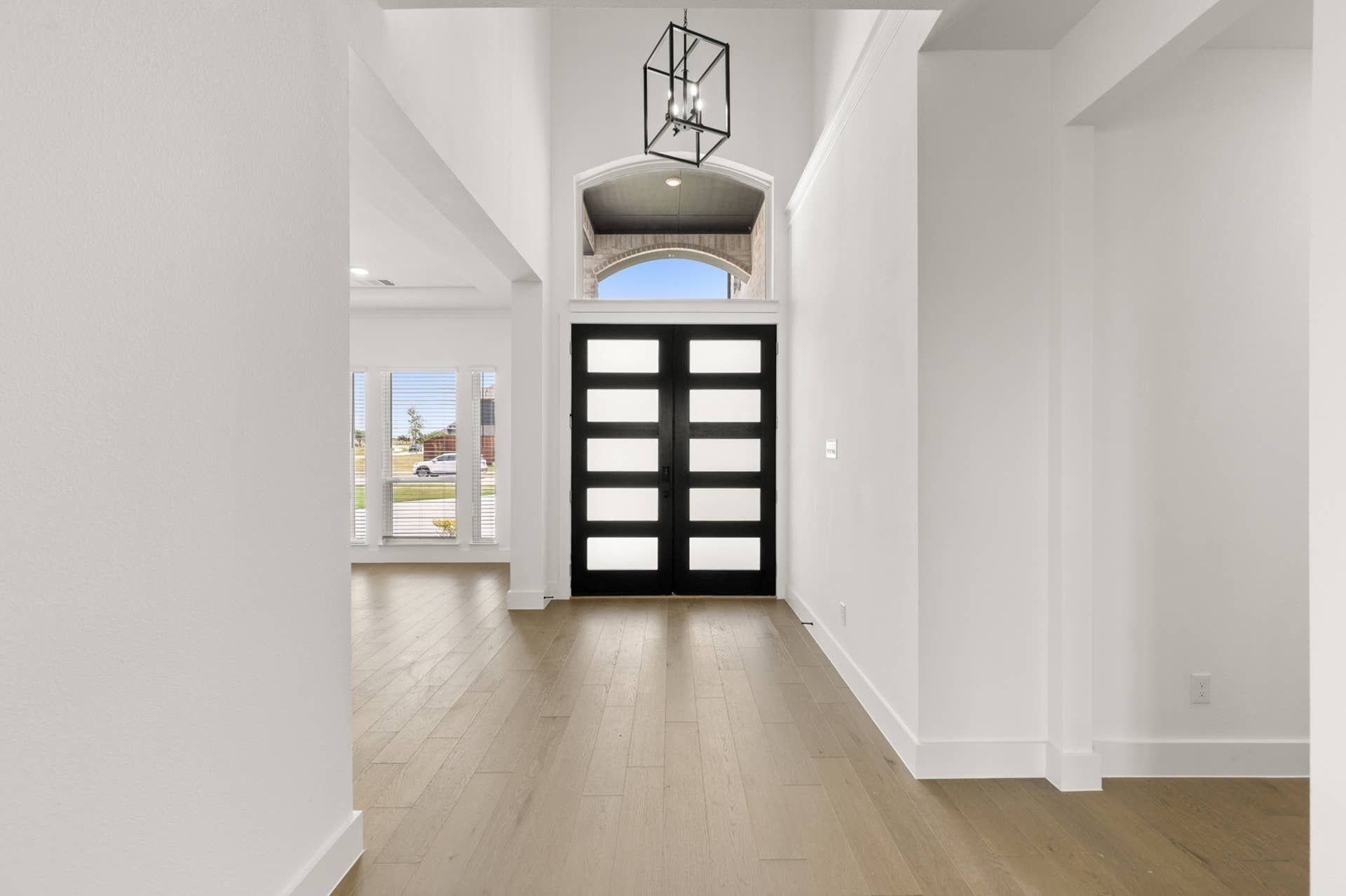 Spacious modern entryway with wooden flooring and contemporary chandelier.