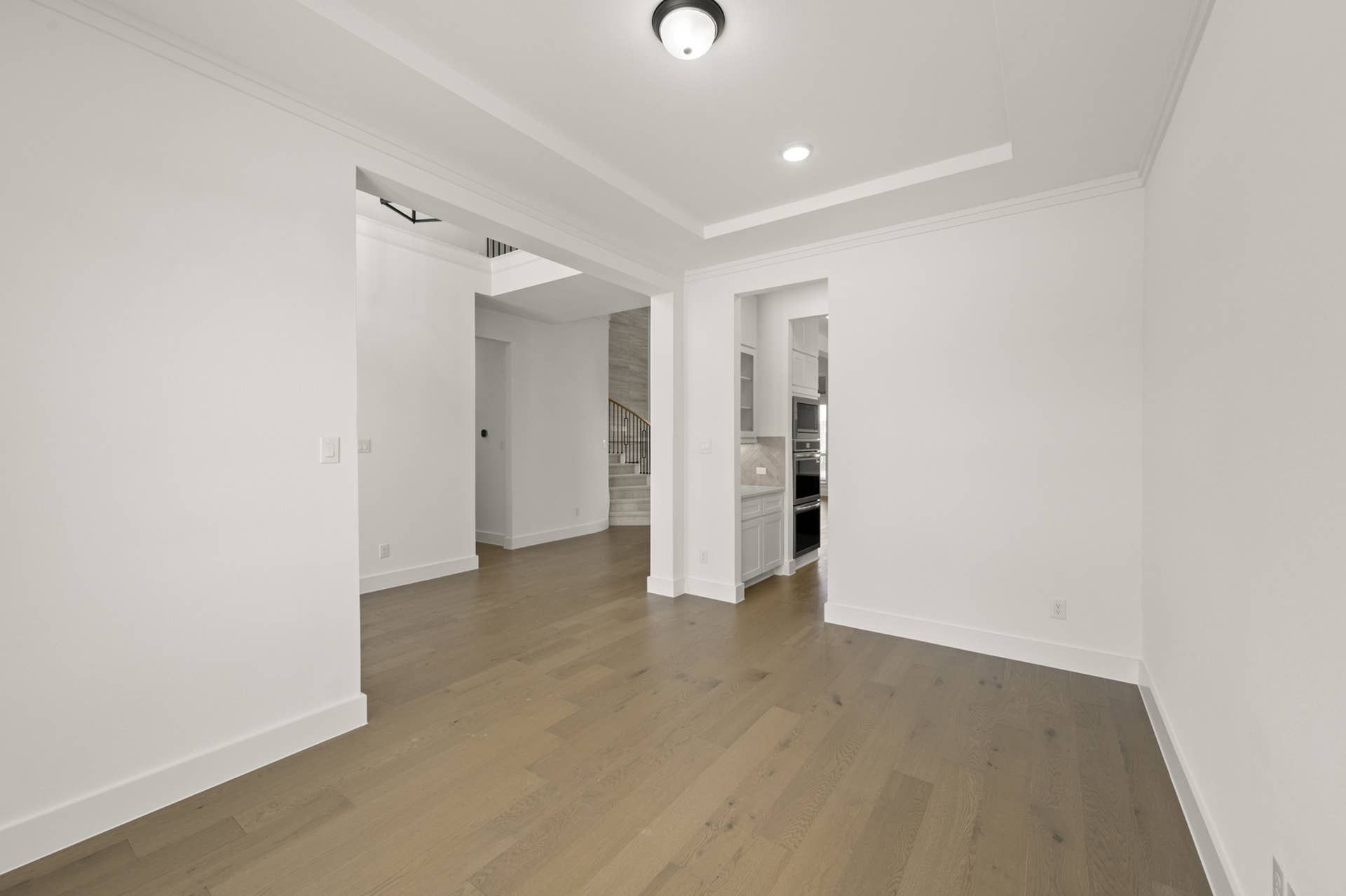Spacious interior with hardwood floors, recessed lighting, and white walls.