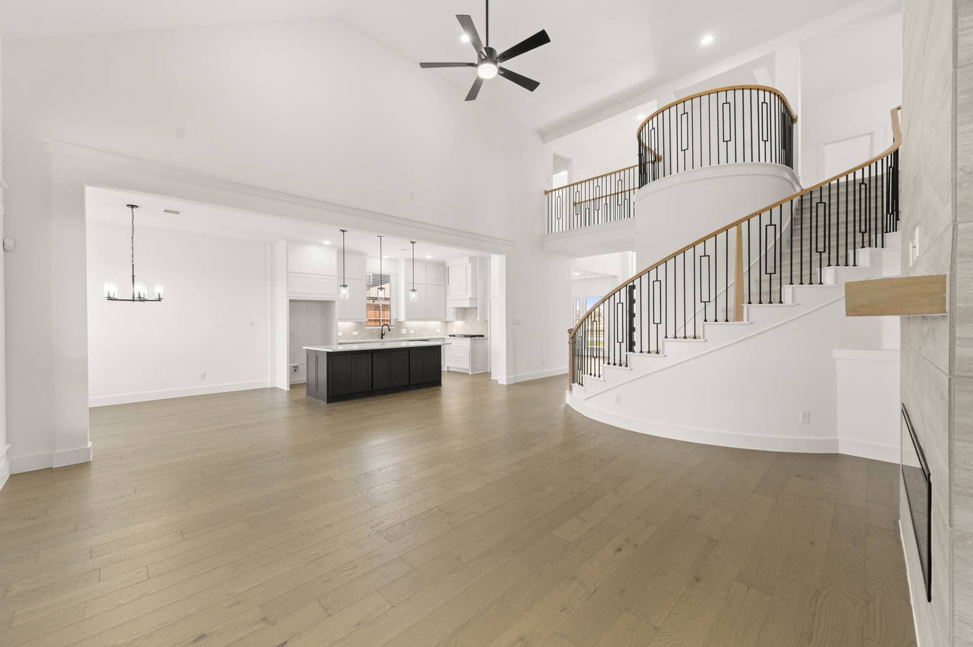 Spacious living room with open kitchen and elegant spiral staircase.