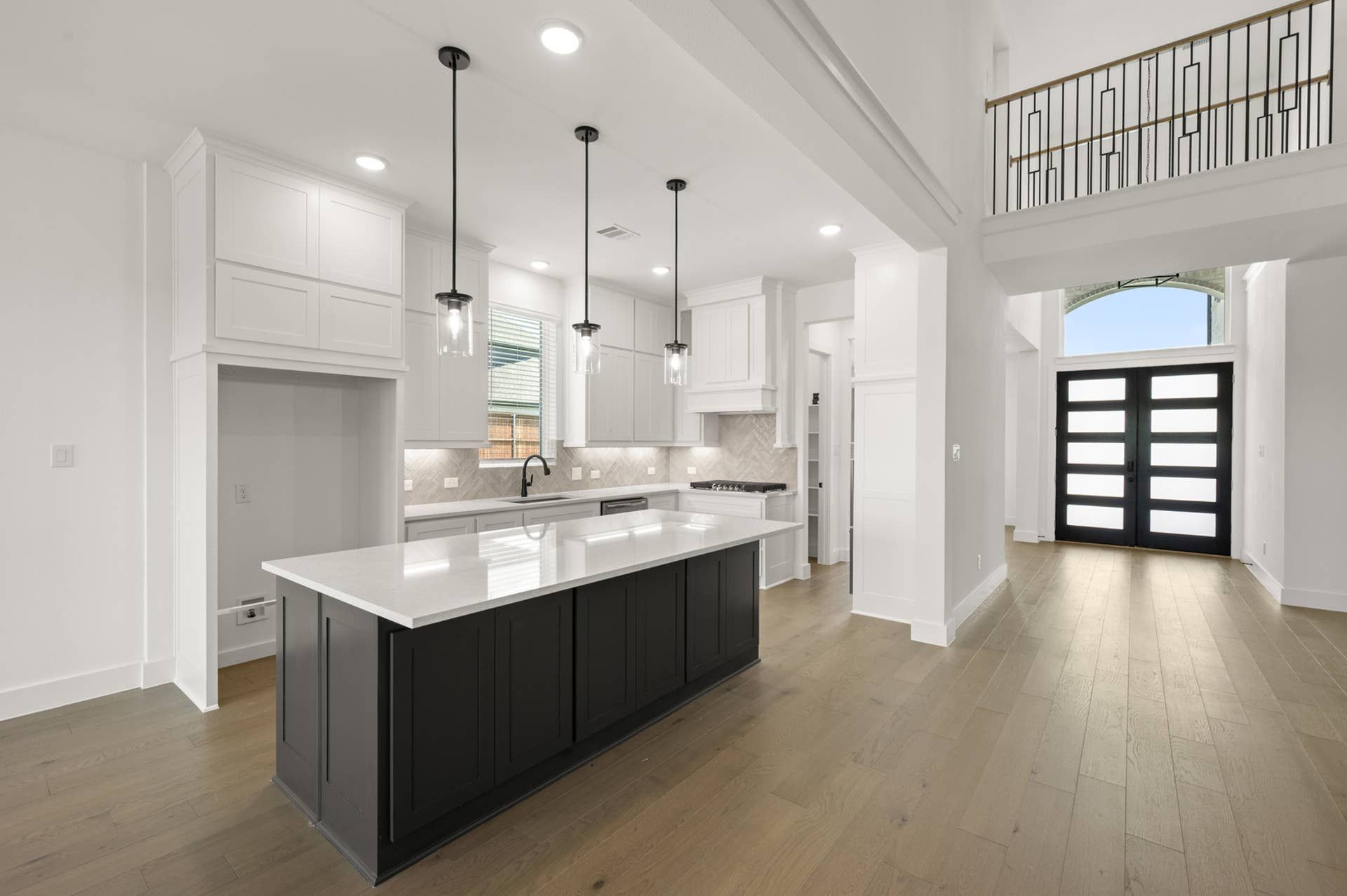 Modern kitchen with island, pendant lights, and elegant entrance view.