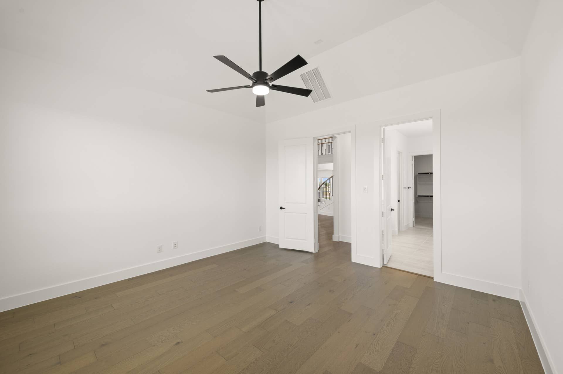 Spacious primary suite with ceiling fan and hardwood floors.