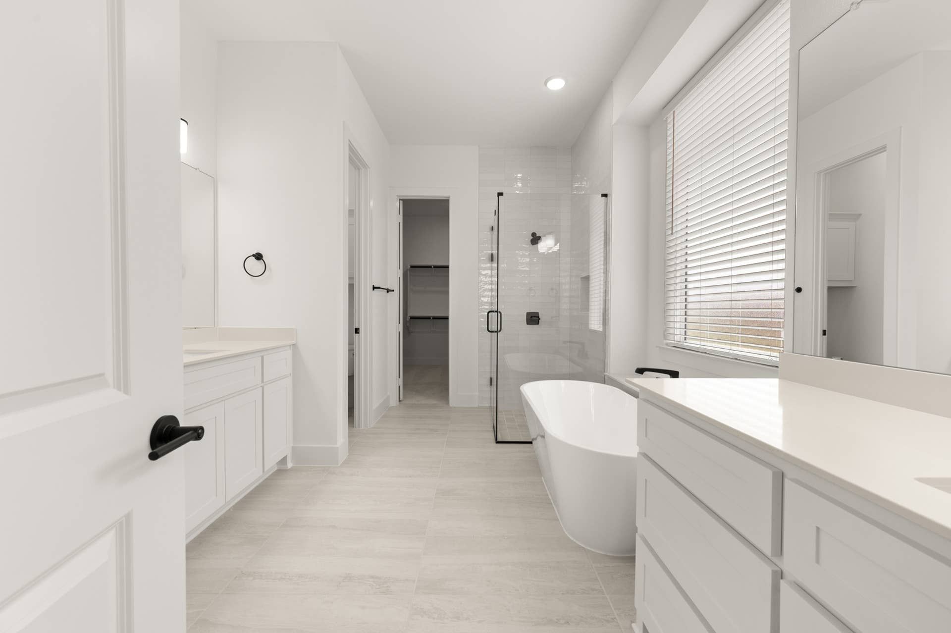 Spacious modern bathroom with freestanding tub, glass shower, and white cabinetry.