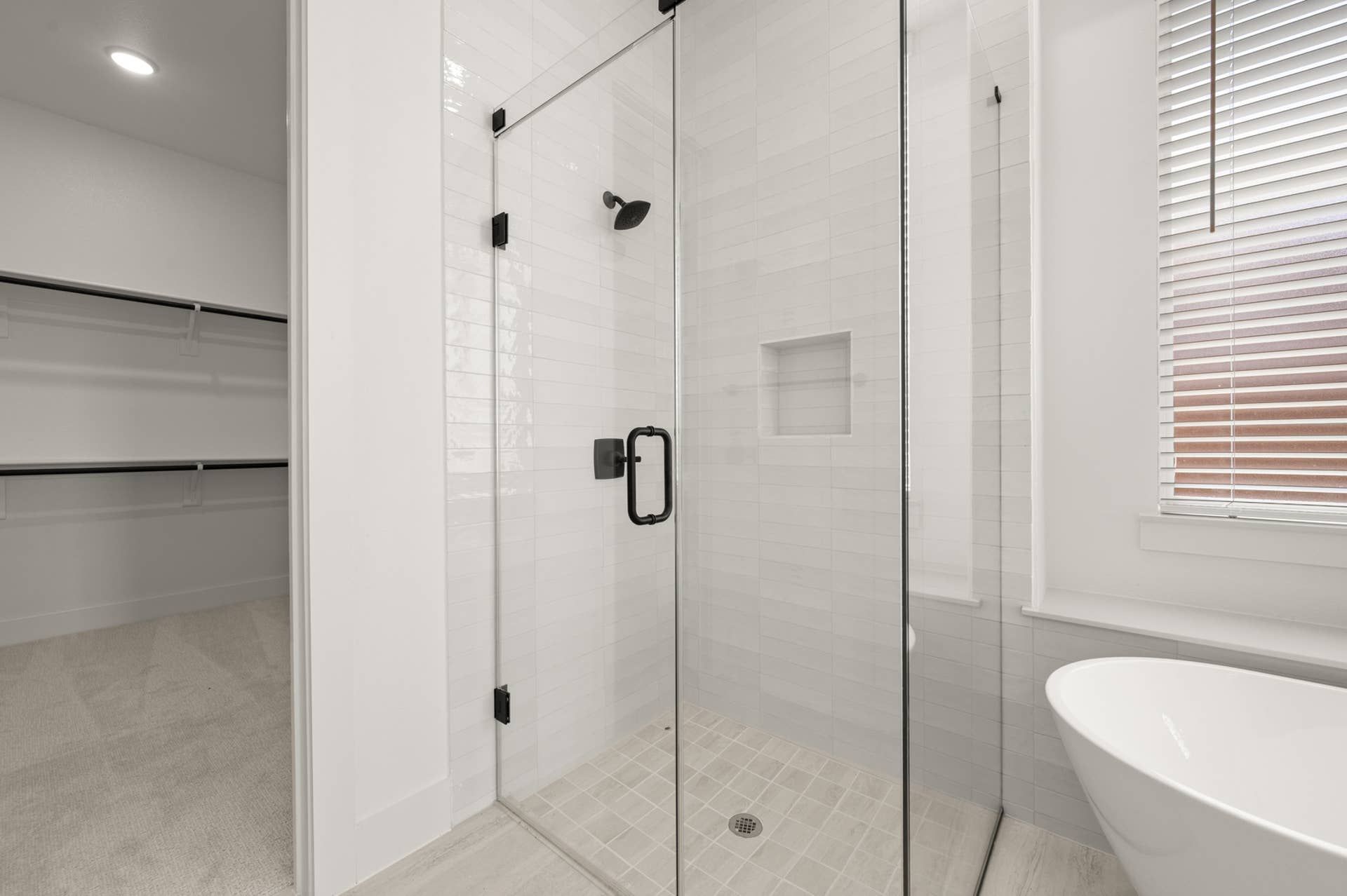 Modern primary suite bathroom with glass shower and freestanding bathtub.