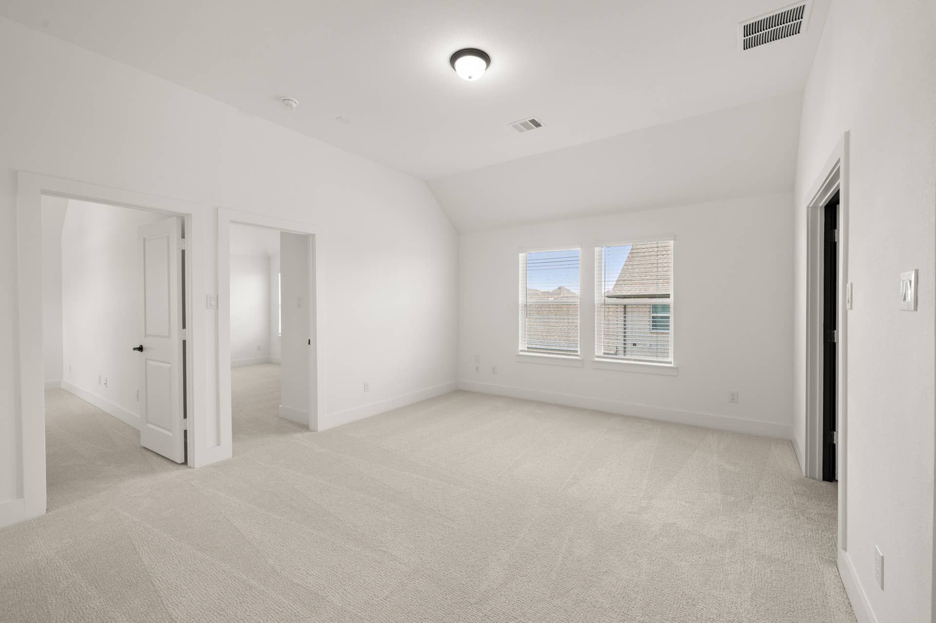 Spacious game room with carpet flooring and natural light from large windows.