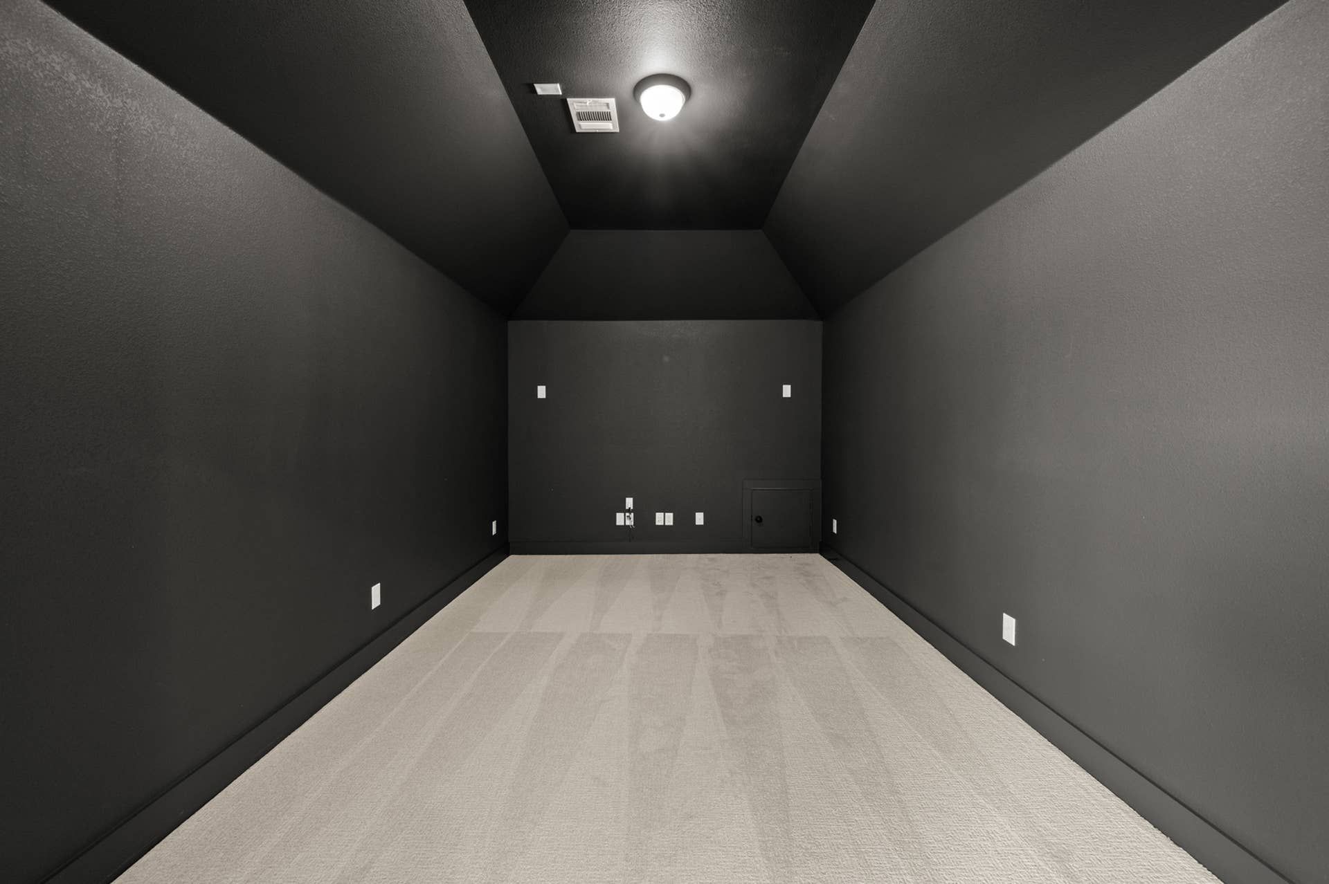 Minimalist black media room with recessed lighting and carpeted floor.