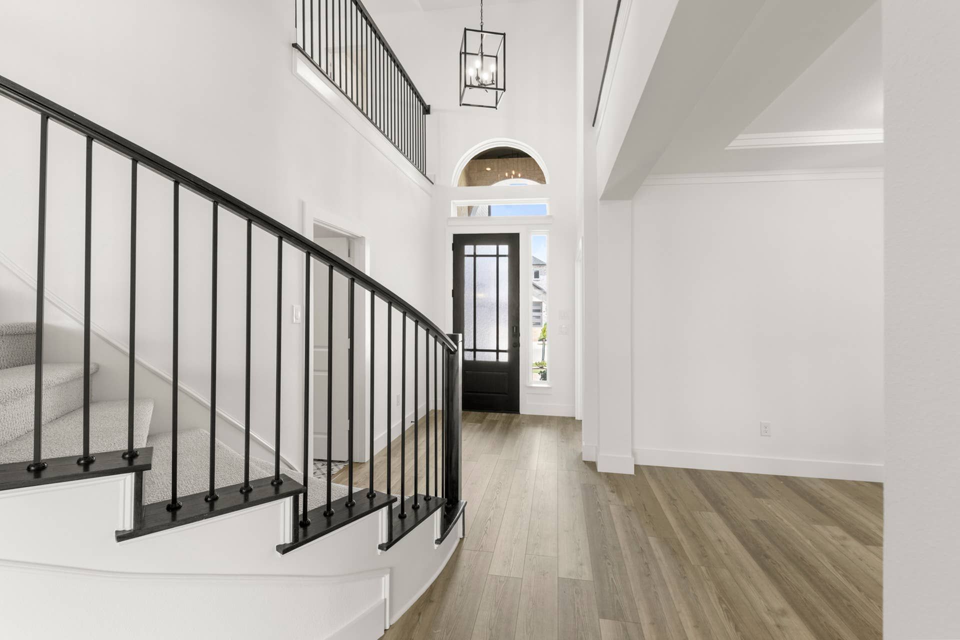 Elegant entryway with curved staircase and black railings.