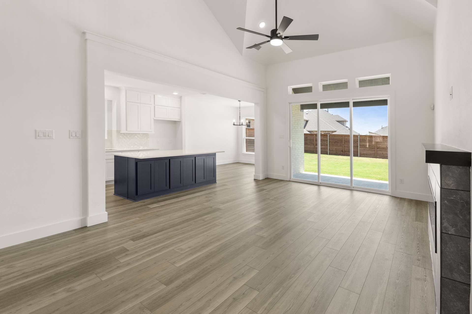 Spacious modern interior with wooden floors and large sliding glass doors to backyard.