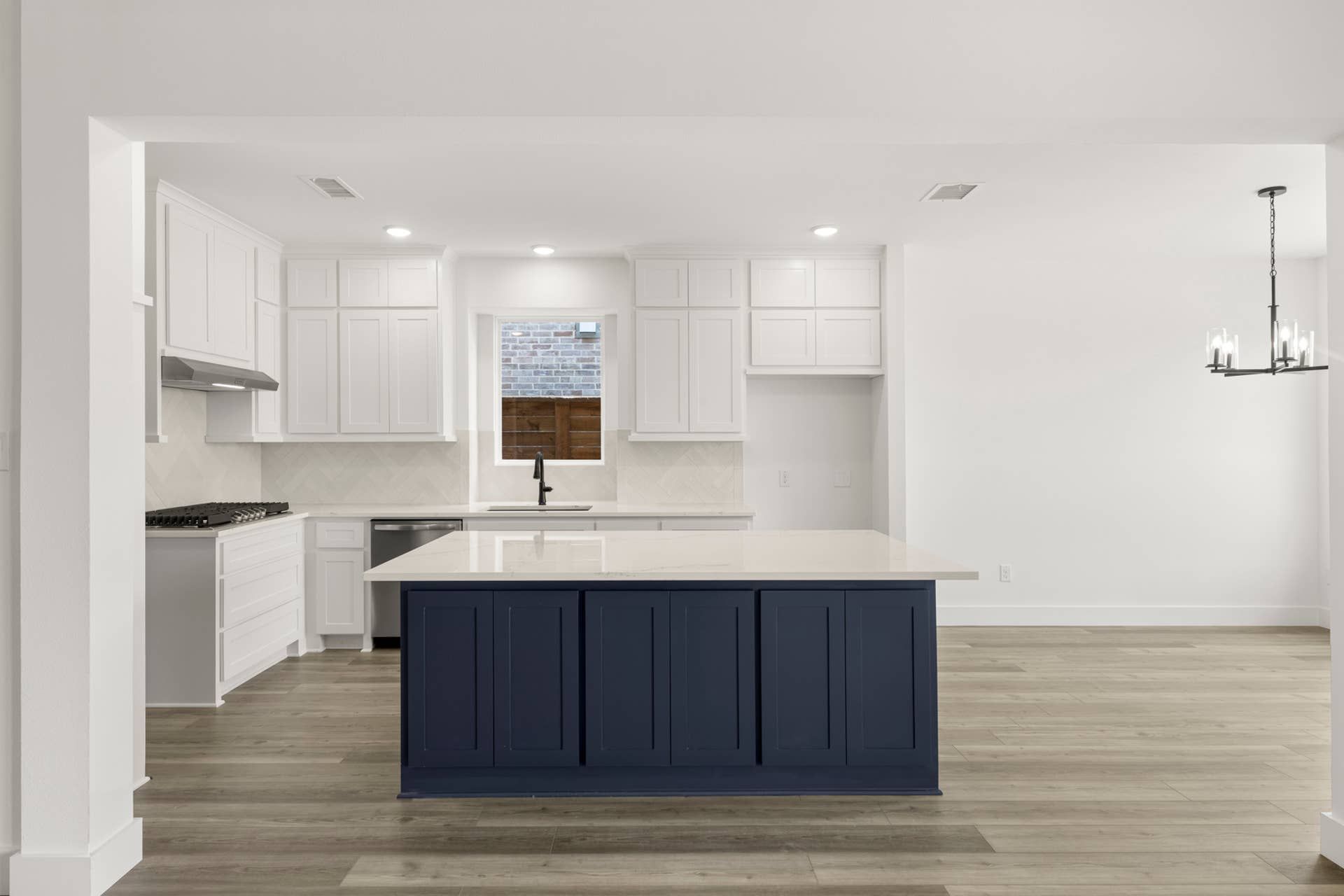 Modern kitchen with navy island, white cabinets, and hardwood floors.