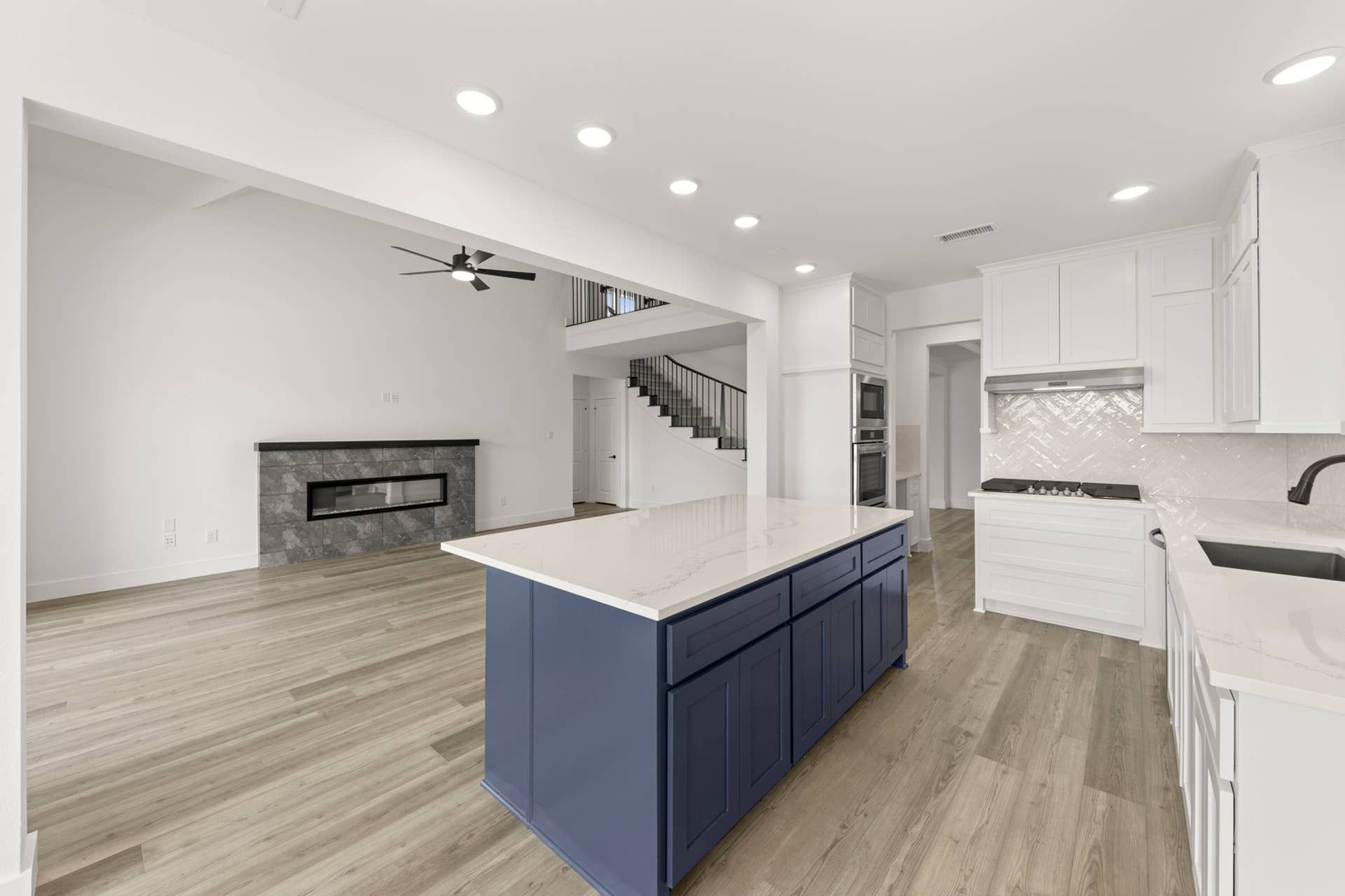 Modern kitchen with blue island, white cabinets, and open living area.